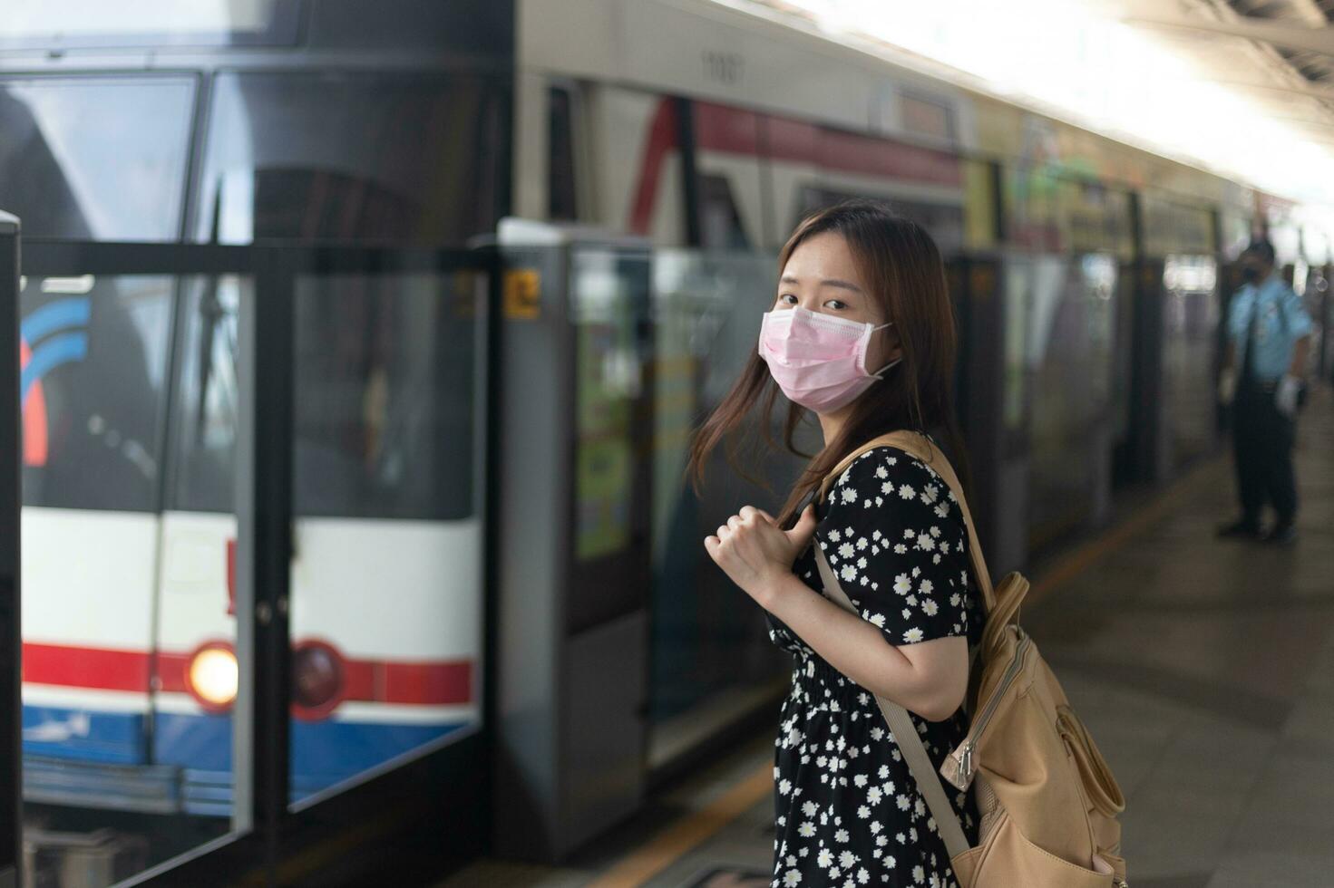 passageiro jovem mulher asiática esperando sua amiga no trem do metrô ao viajar na cidade grande foto