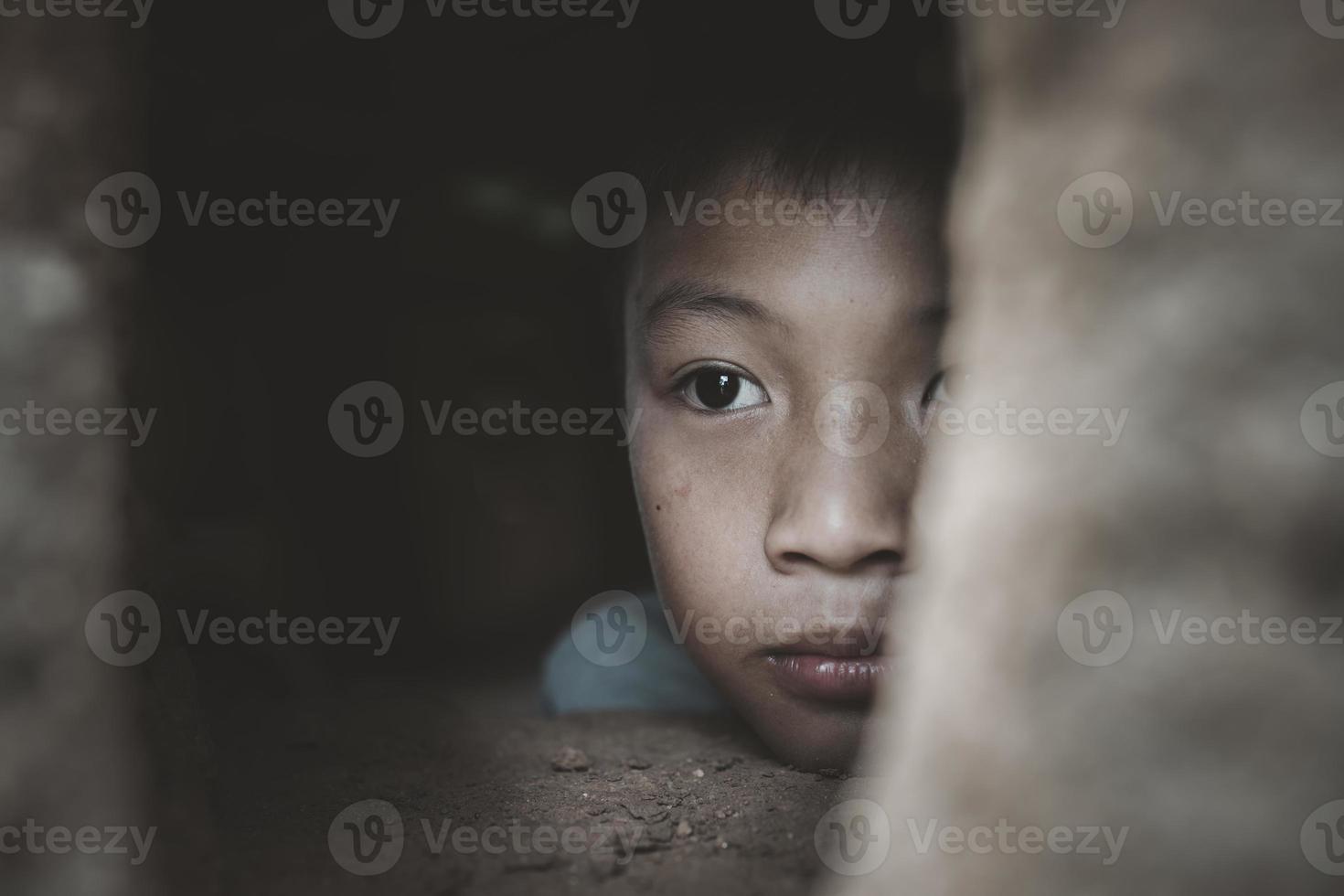 closeup menino pobre espreitando de uma casa em ruínas, conceito de assistência aos pobres, direitos humanos. foto