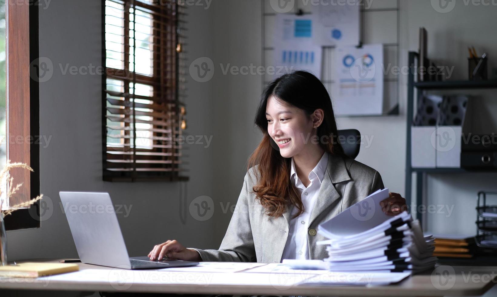 encantadora empresária asiática sentada trabalhando no laptop no escritório. foto