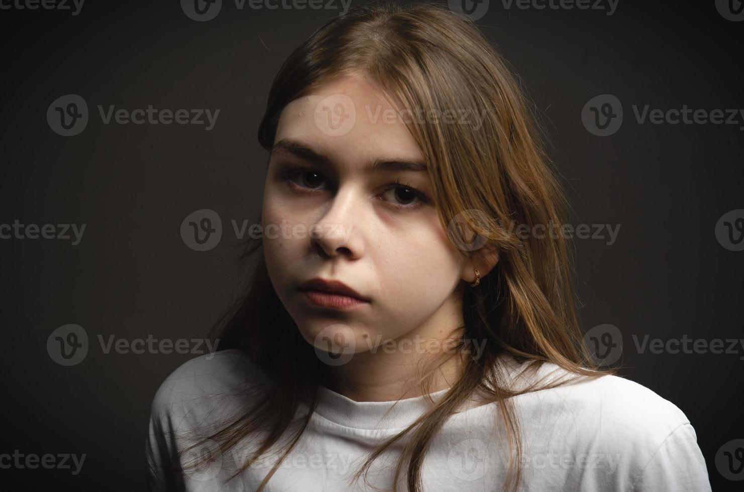 retrato de uma garota em uma camiseta branca em um fundo escuro foto