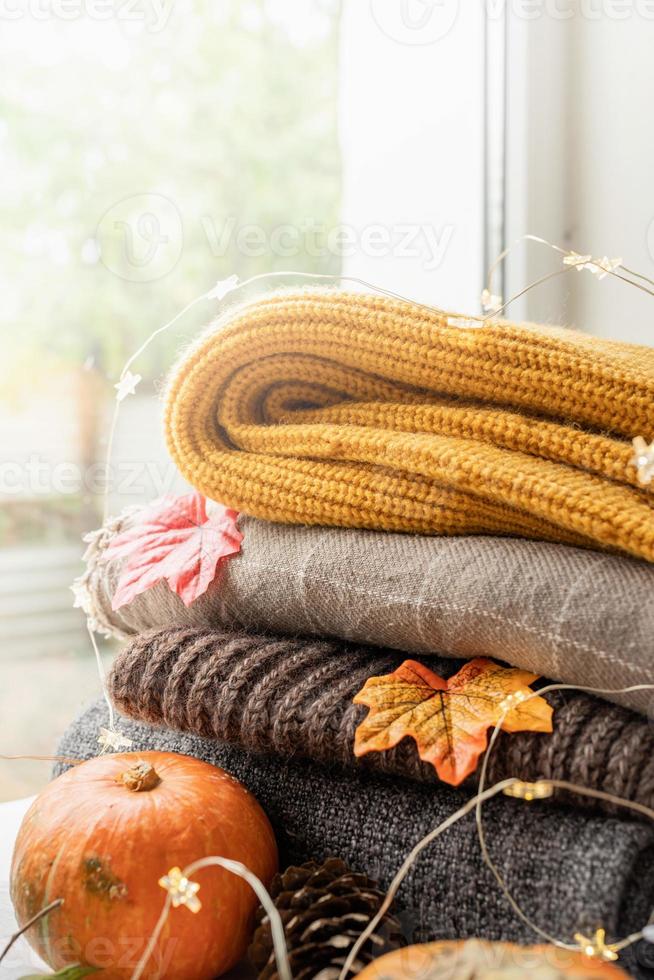 composição de outono aconchegante, clima de suéter. pilha de blusas quentes na janela foto