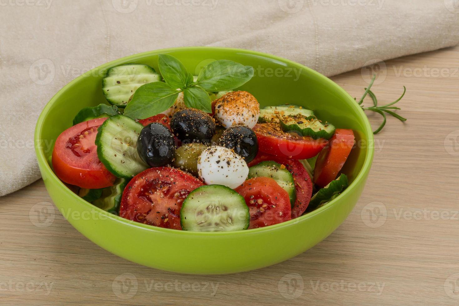 salada com mussarela e tomate em uma tigela sobre fundo de madeira foto