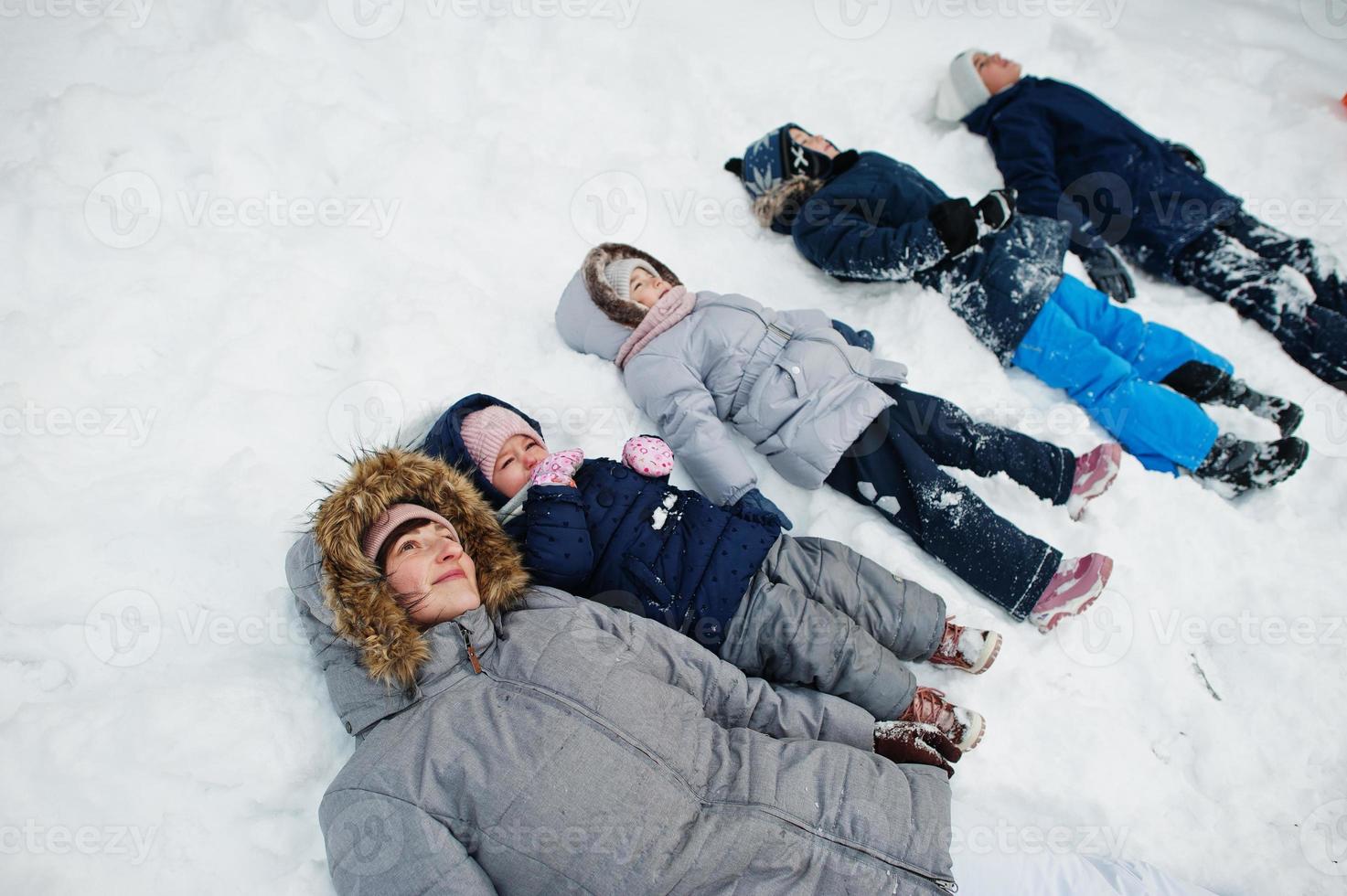 mãe com quatro filhos na natureza de inverno deitado na neve. foto