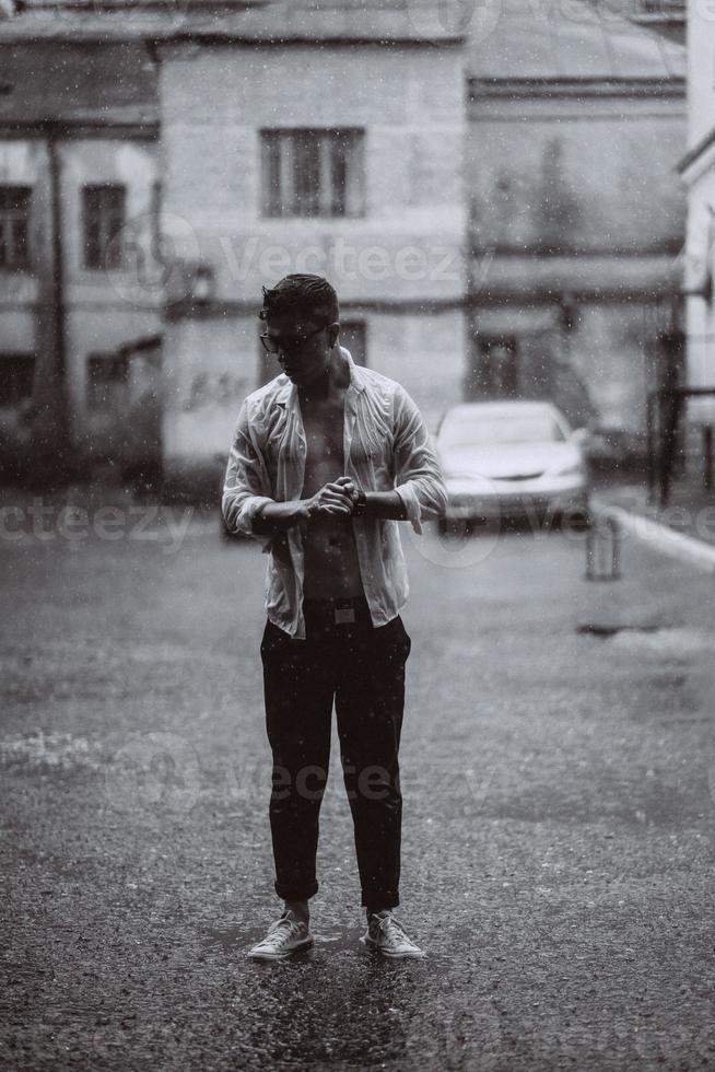 retrato de jovem bonito despreocupado está se sentindo livre sob a chuva foto