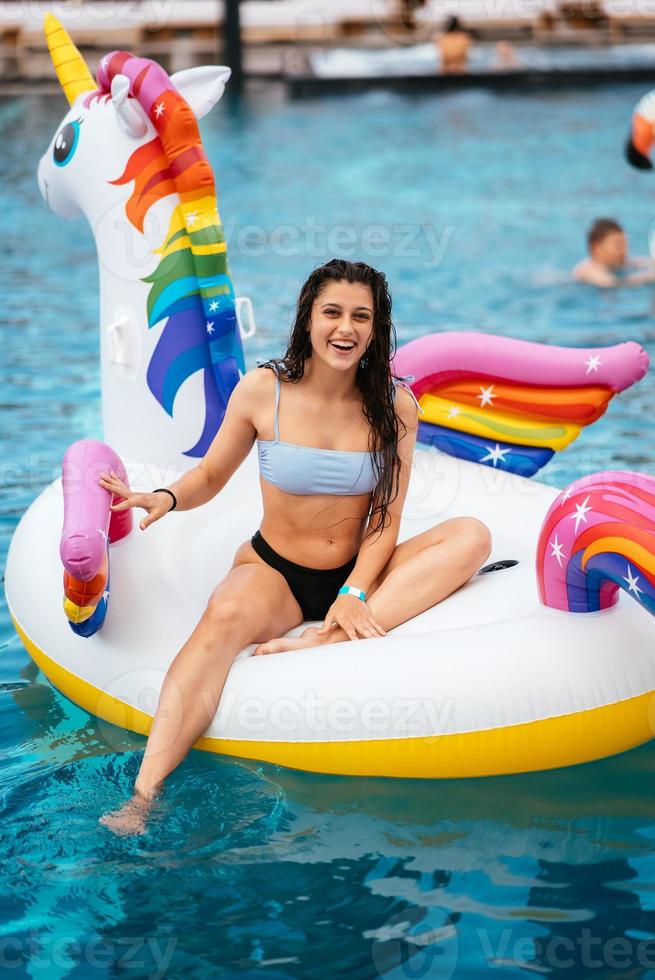 mulher no colchão de brinquedo inflável unicórnio flutua na piscina. foto