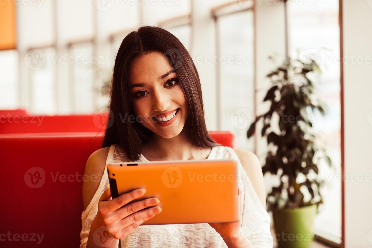 linda garota trabalhando em um tablet e sorrindo. efeito de tonificação do instagram foto