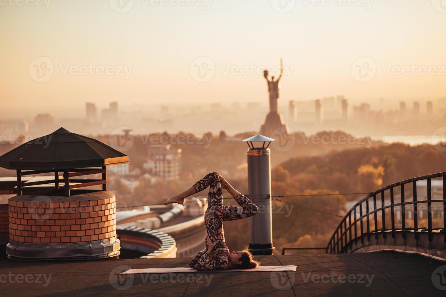 mulher fazendo ioga no telhado de um arranha-céu na cidade grande. foto