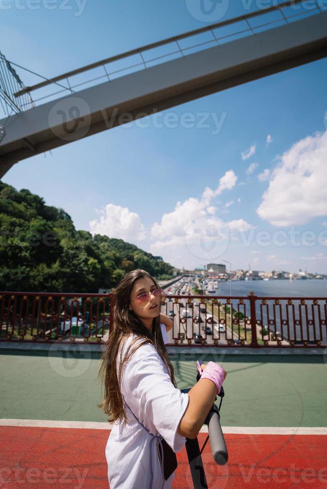 jovem mulher bonita e uma scooter elétrica, transporte ecológico foto