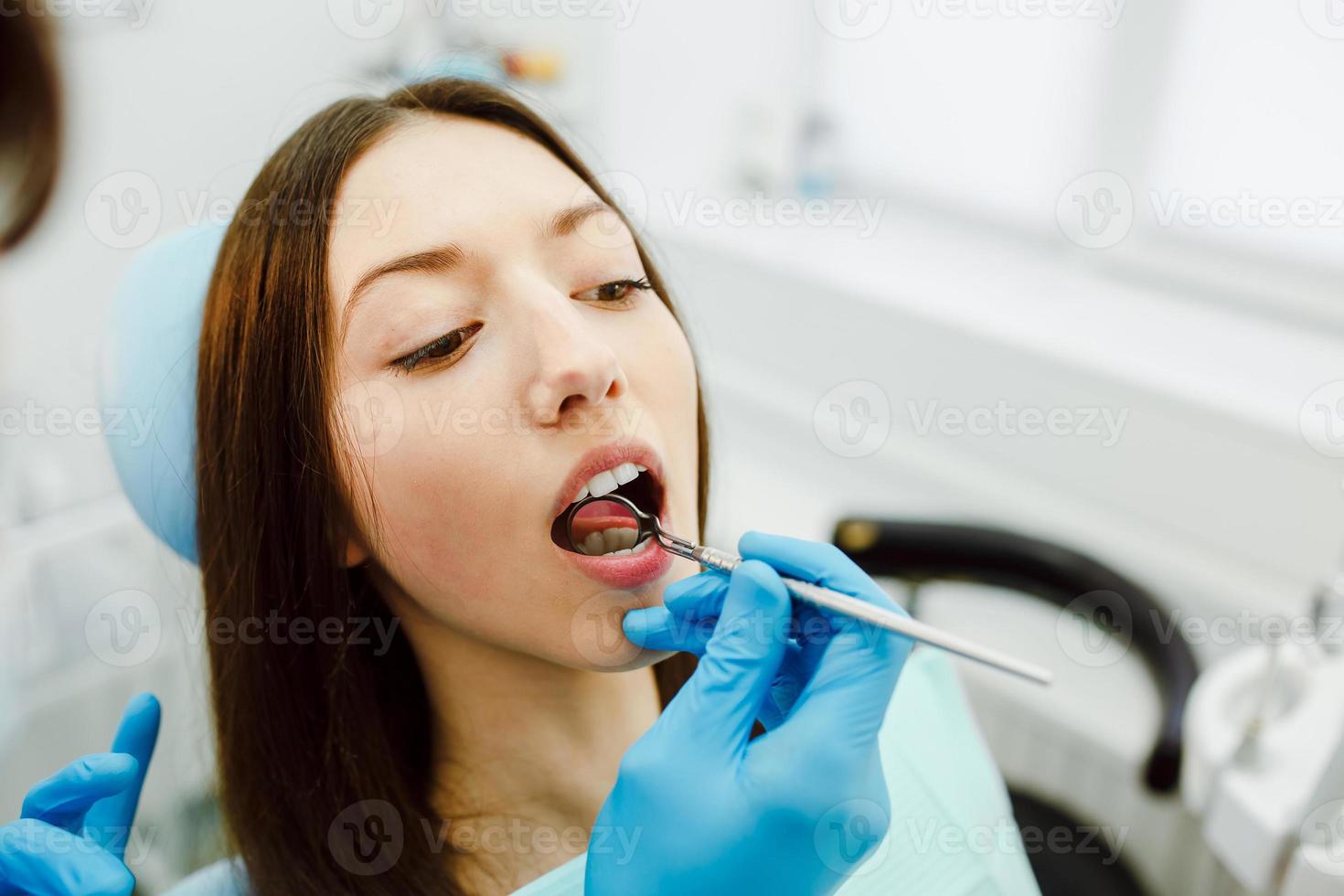 inspeção dos dentes da menina com a ajuda de um espelho foto