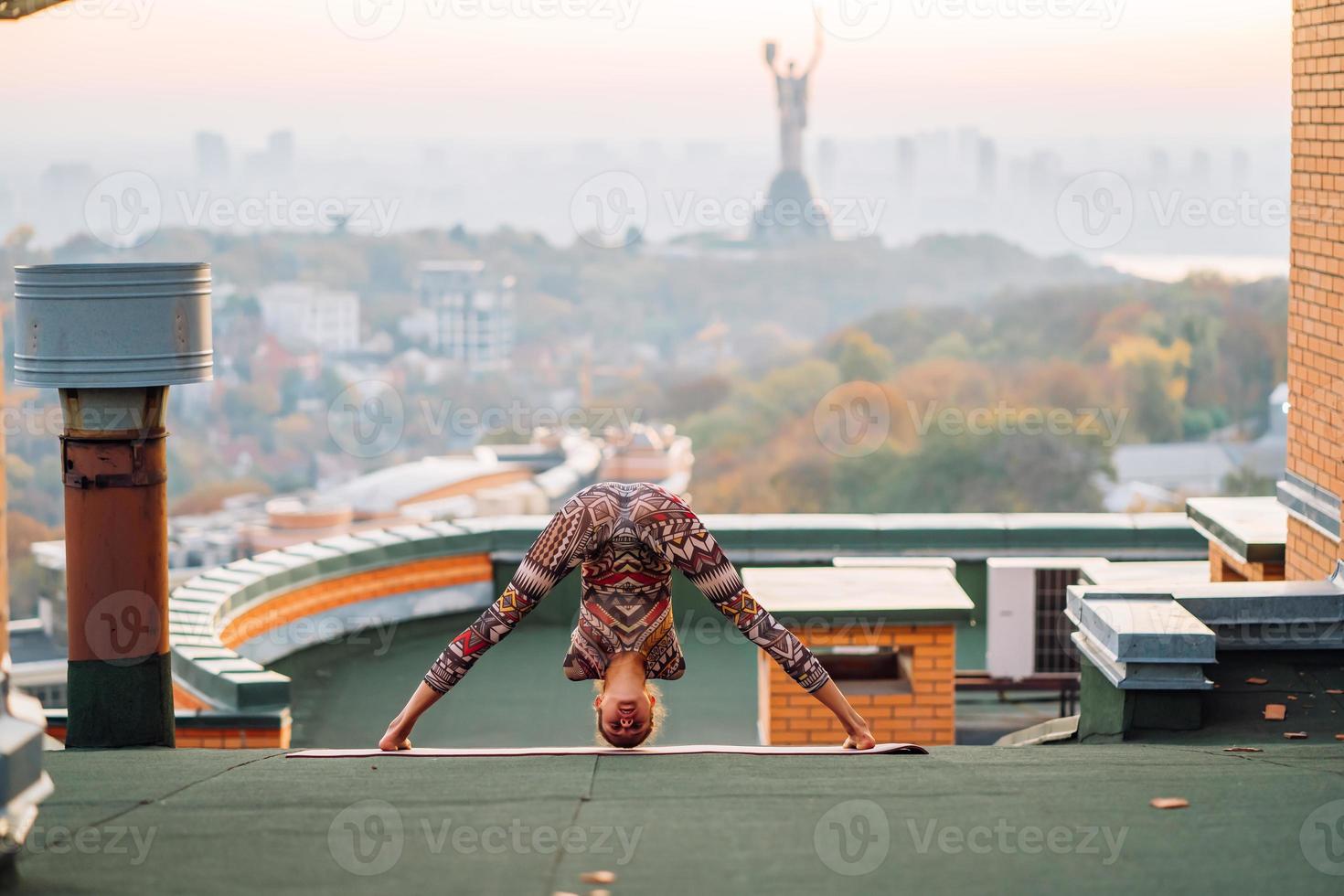 mulher fazendo ioga no telhado de um arranha-céu na cidade grande. foto