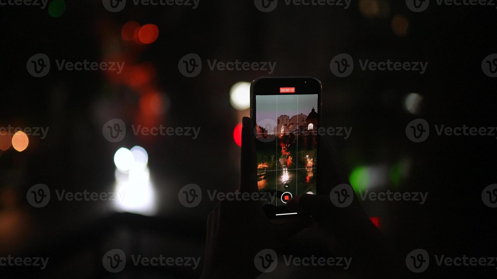 homem grava vídeo da rua noturna em um smartphone foto