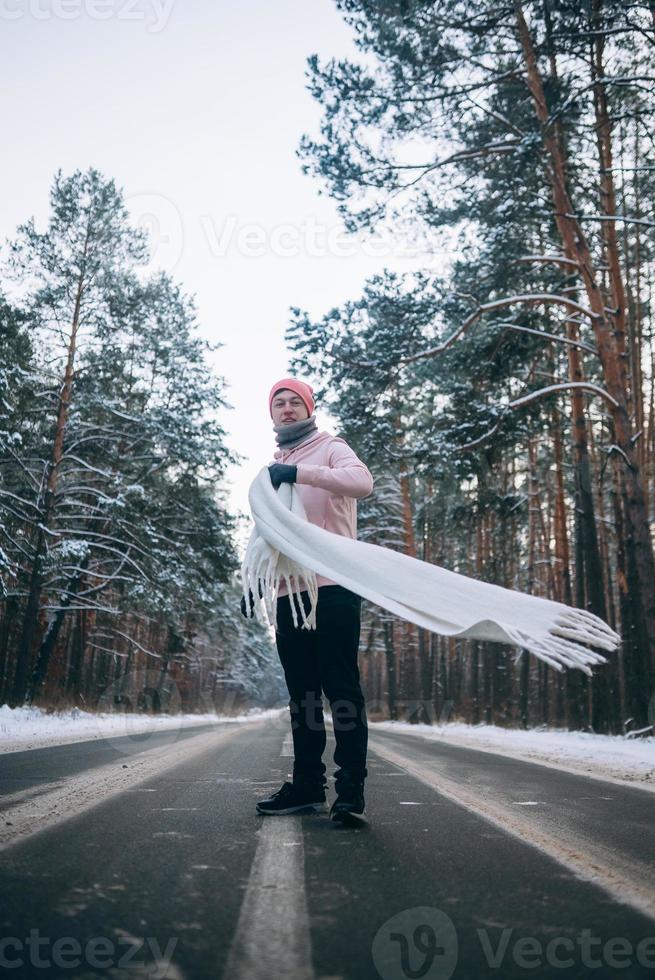 cara parado na estrada no meio da floresta, cercado por neve foto