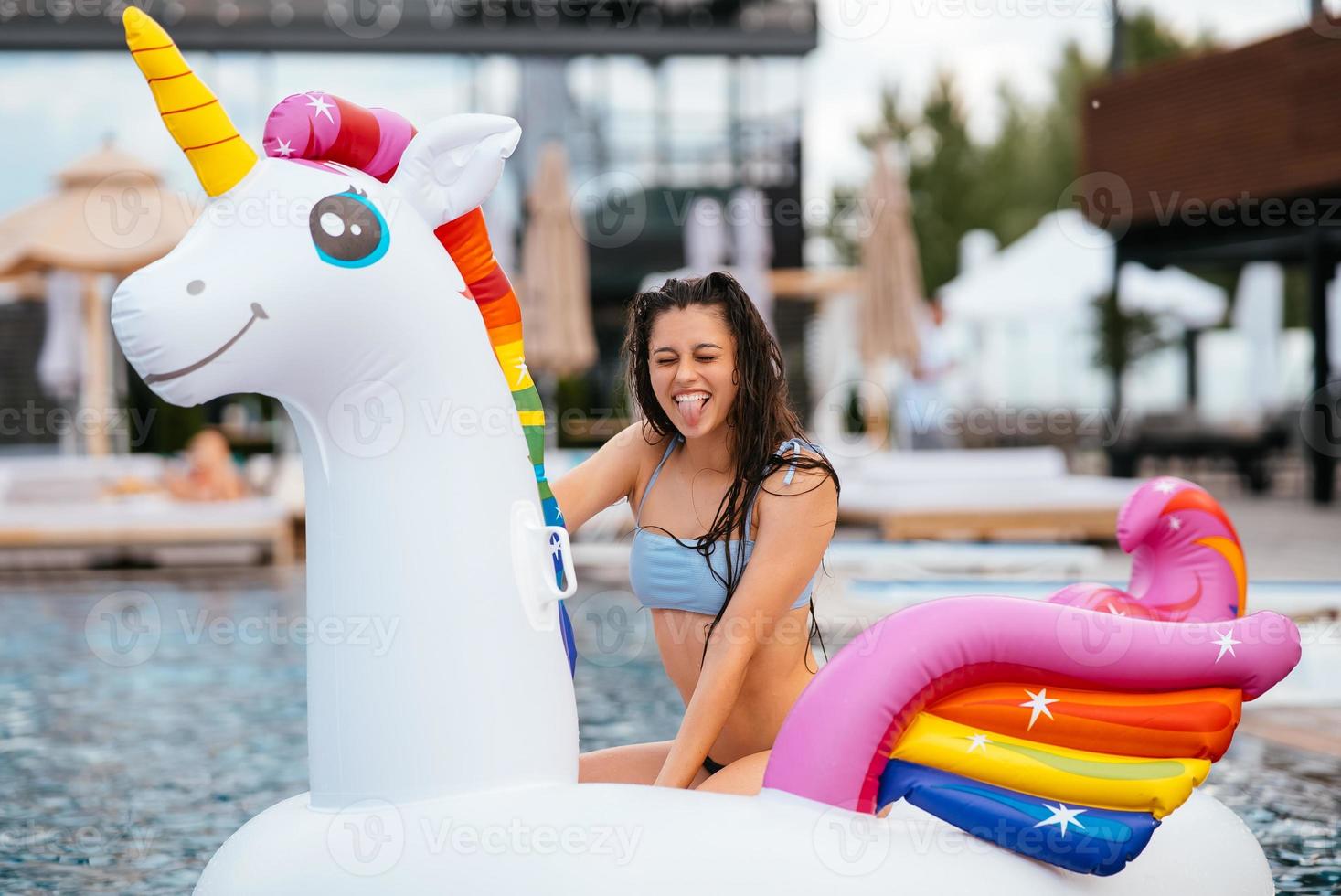 mulher no colchão de brinquedo inflável unicórnio flutua na piscina. foto