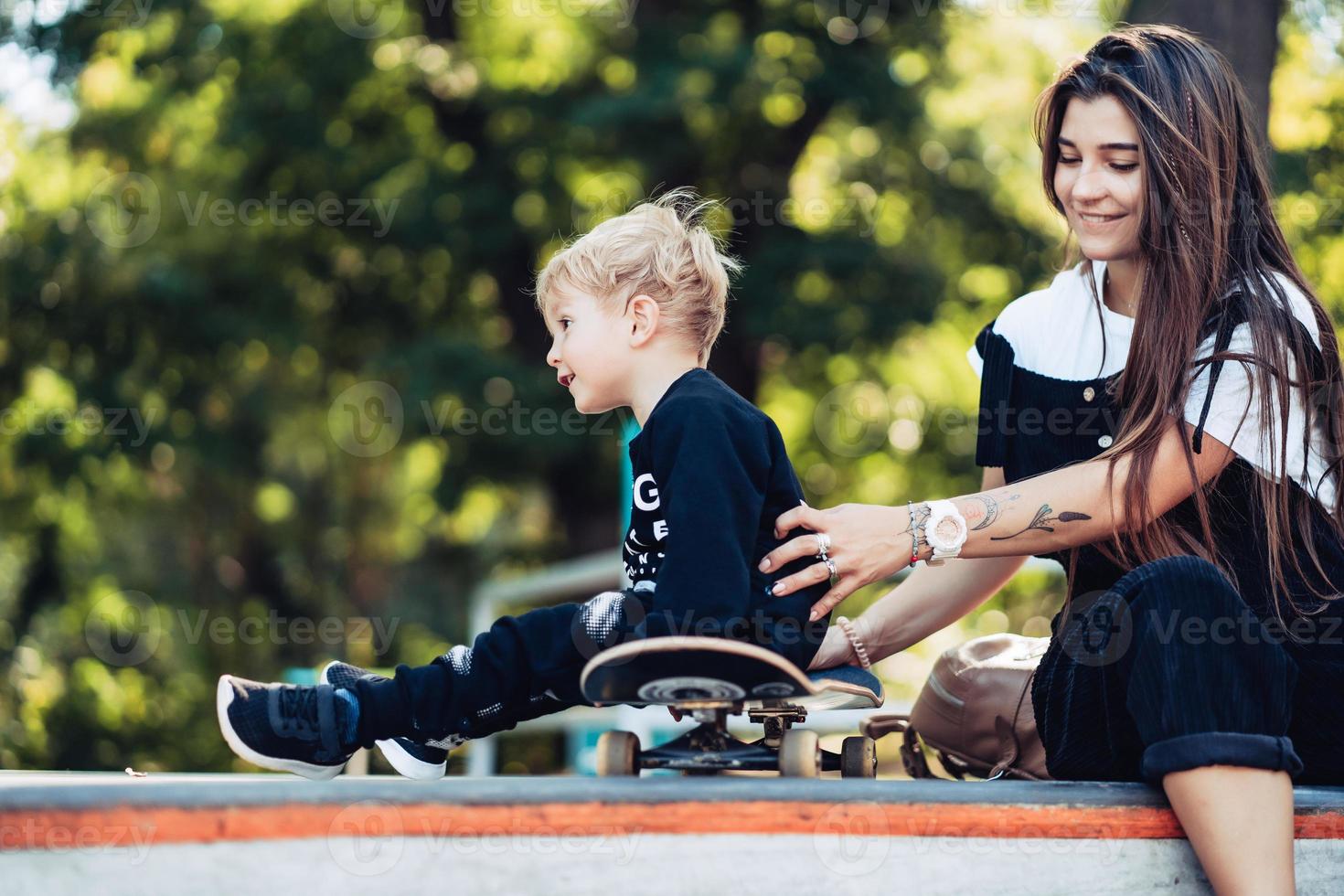 bela jovem hipster mãe e filho no skatepark foto