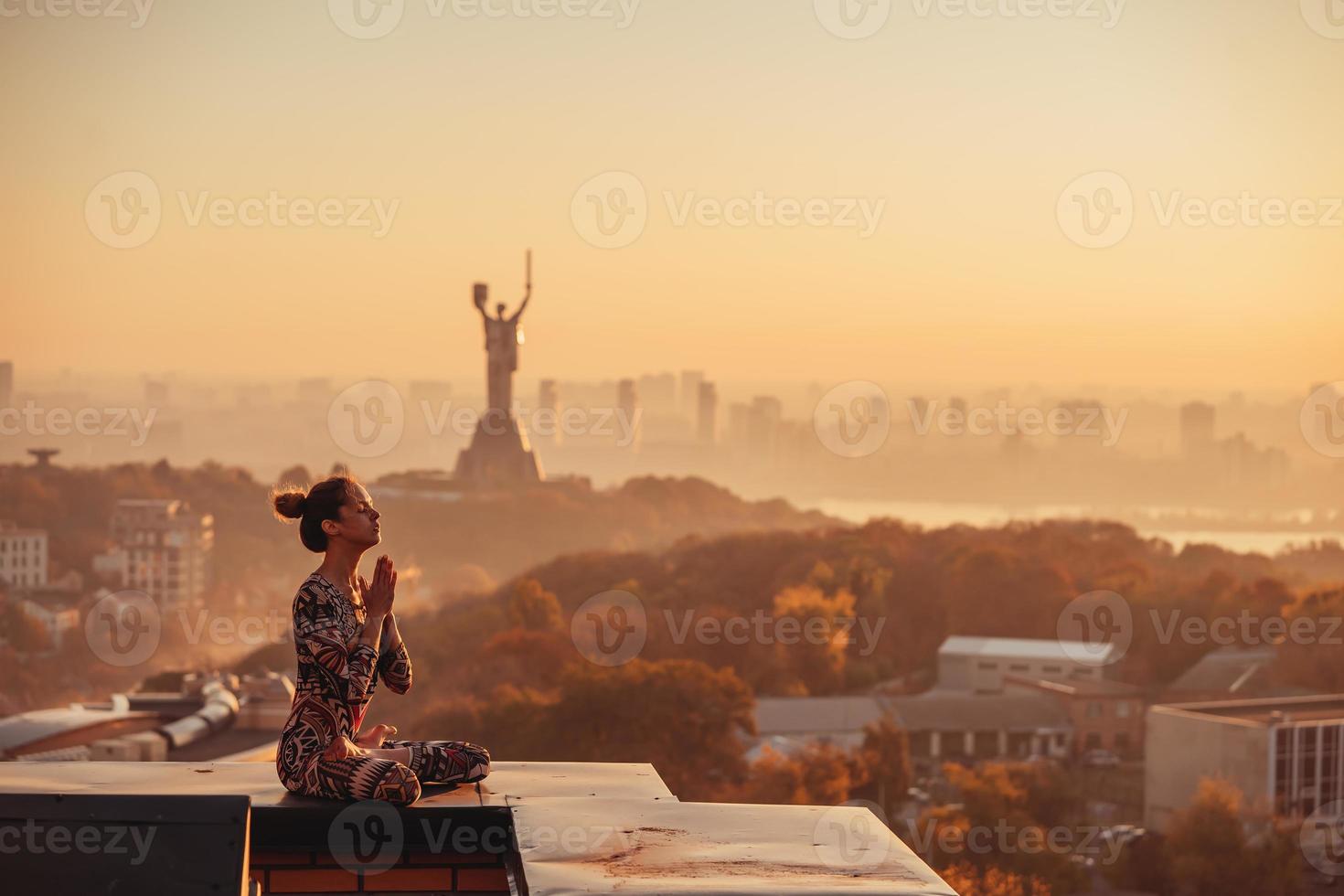mulher fazendo ioga no telhado de um arranha-céu na cidade grande. foto