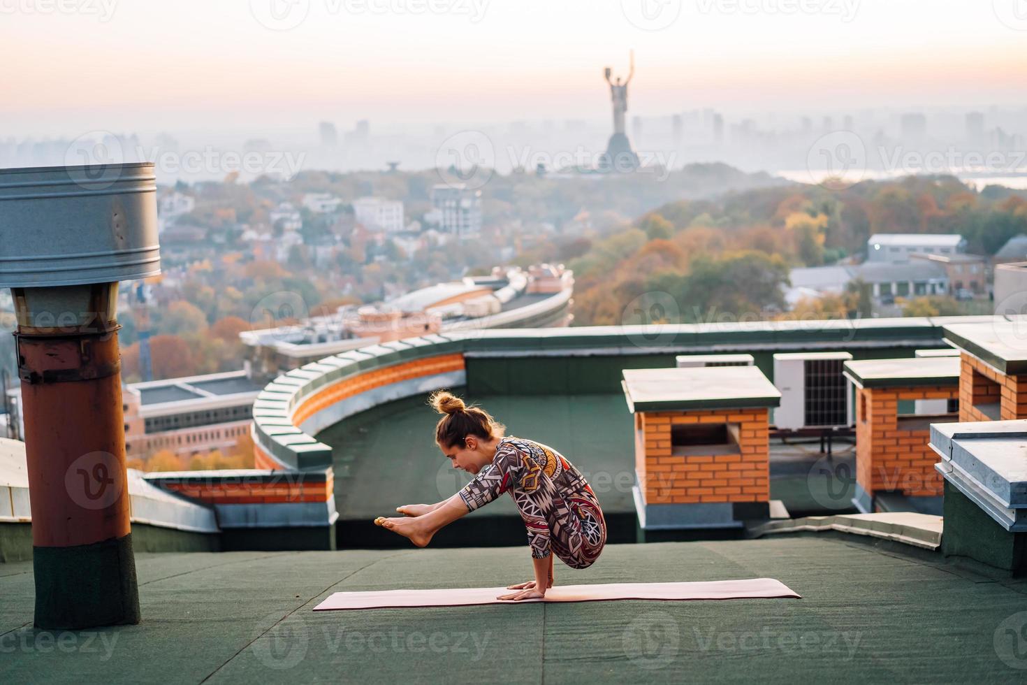 mulher fazendo ioga no telhado de um arranha-céu na cidade grande. foto