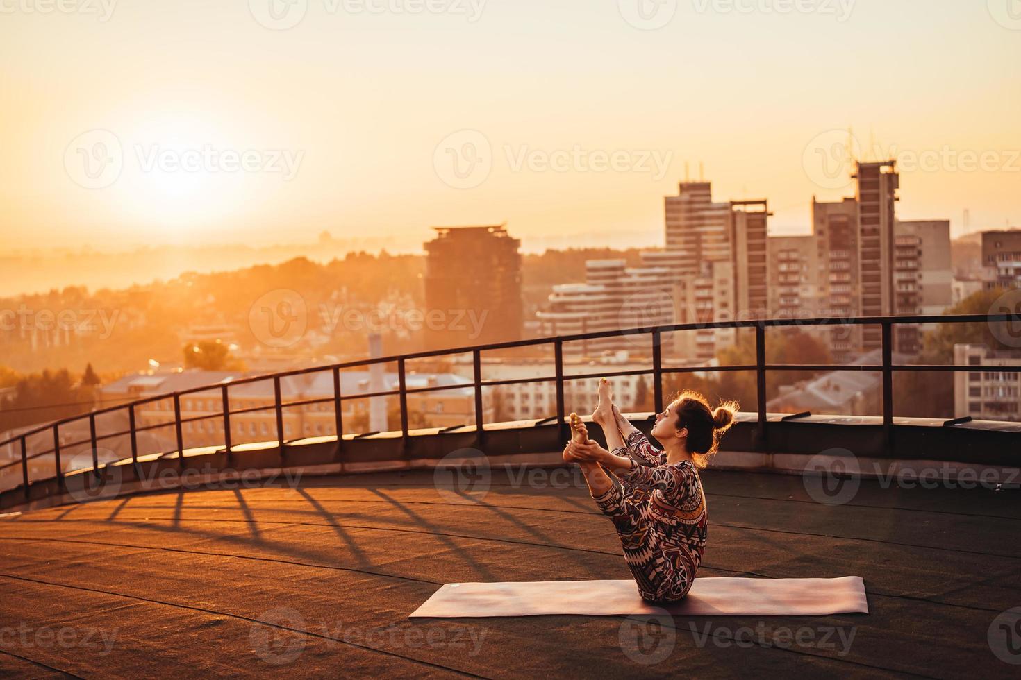 mulher fazendo ioga no telhado de um arranha-céu na cidade grande. foto