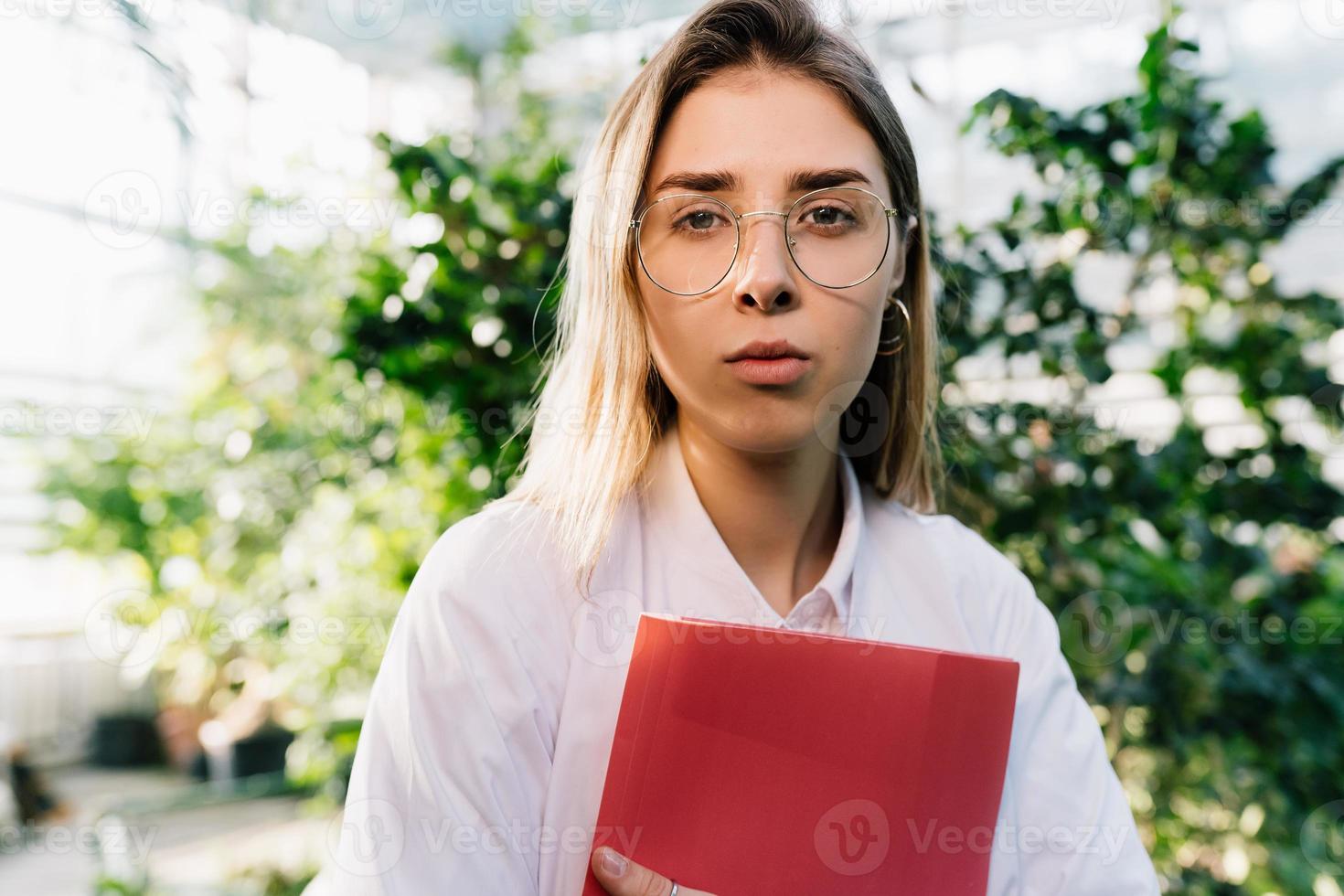 jovem engenheiro agrônomo trabalhando em estufa. jovem cientista feminina olhando para a câmera foto