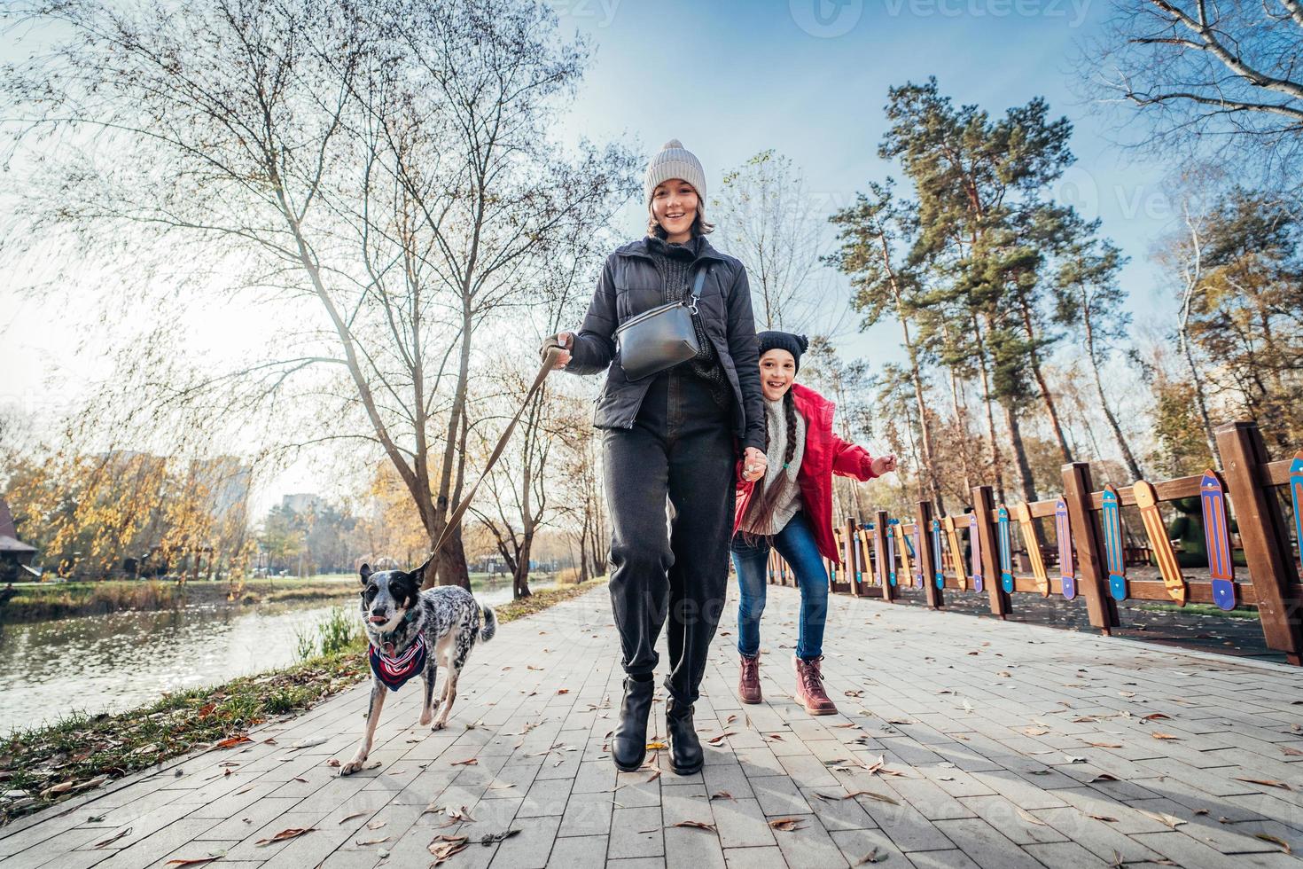 feliz mãe e filha andam com cachorro no parque outono foto