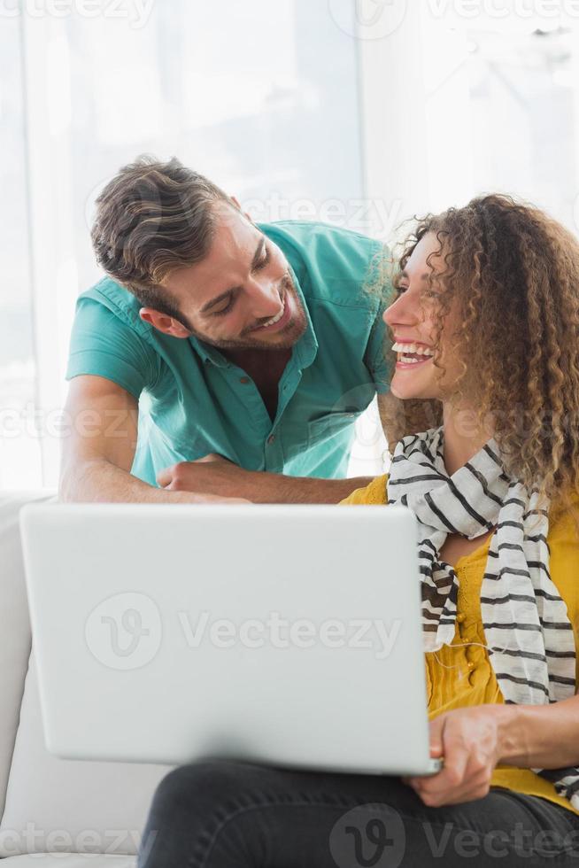 mulher sorridente no sofá mostrando seu colega seu laptop foto