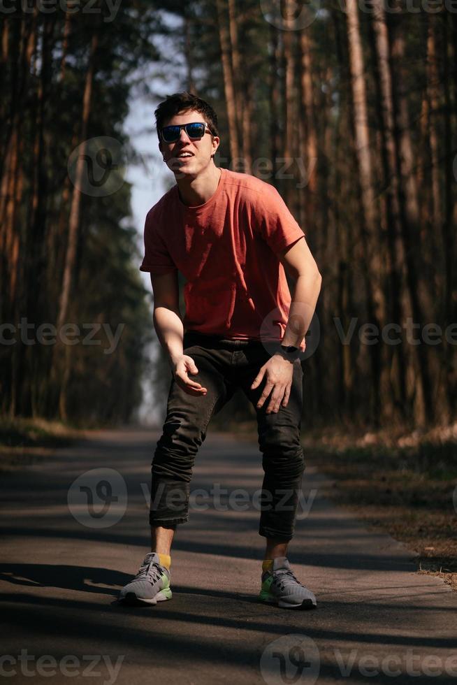 jovem bonito de camiseta branca e jeans ao ar livre no parque, andando no parque foto