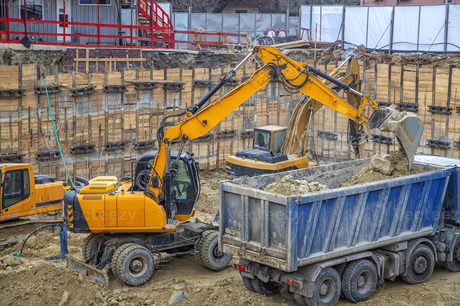 escavadeira está carregando a escavação no caminhão. equipamentos de construção pesada trabalhando no canteiro de obras. foto