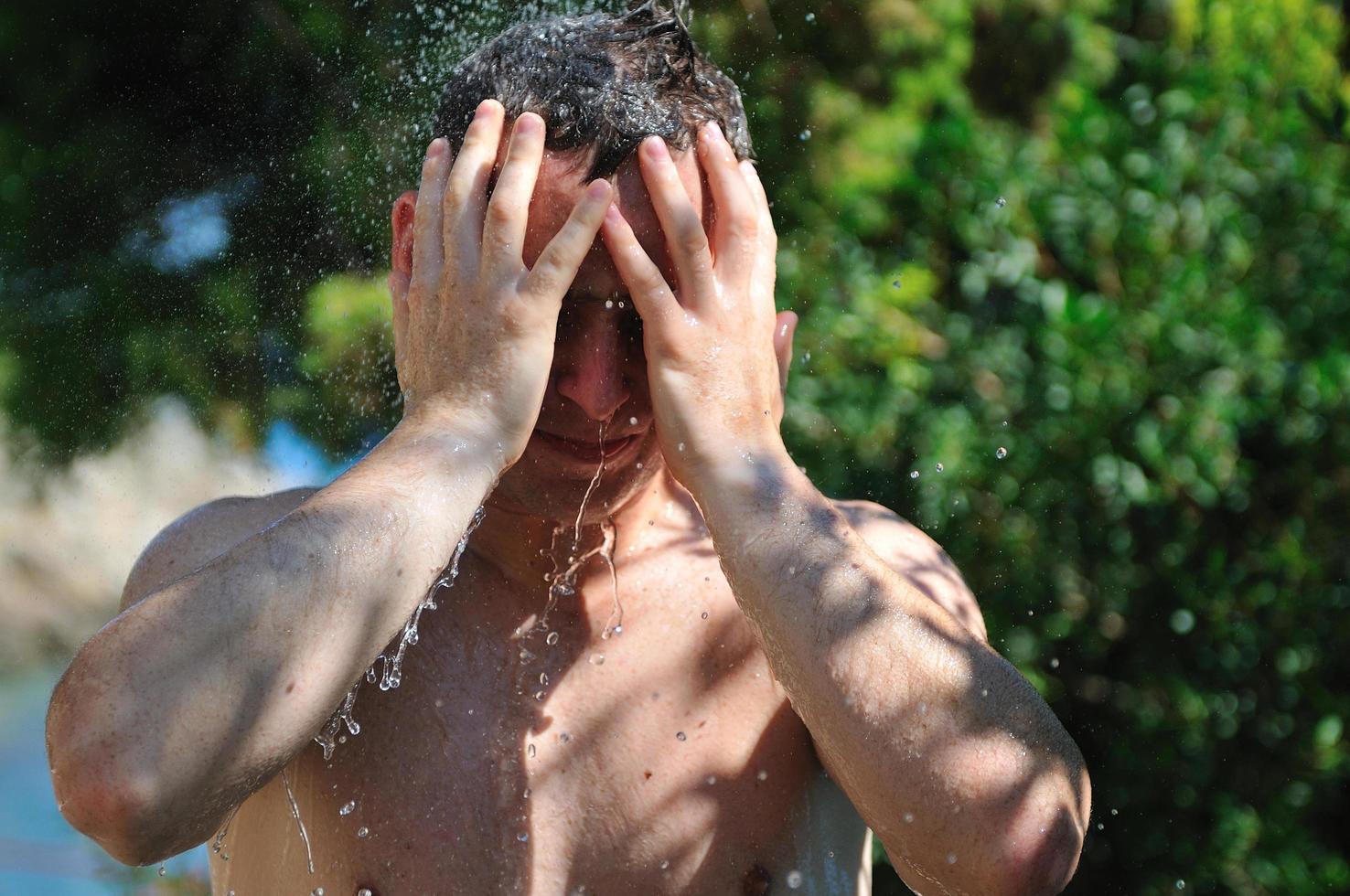 jovem relaxante sob o chuveiro foto