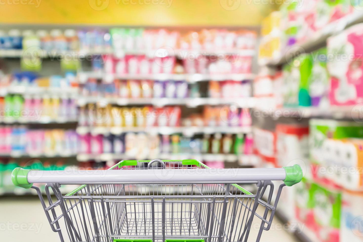 prateleiras de detergente e produtos de limpeza no supermercado ou mercearia com carrinho de compras vazio foto