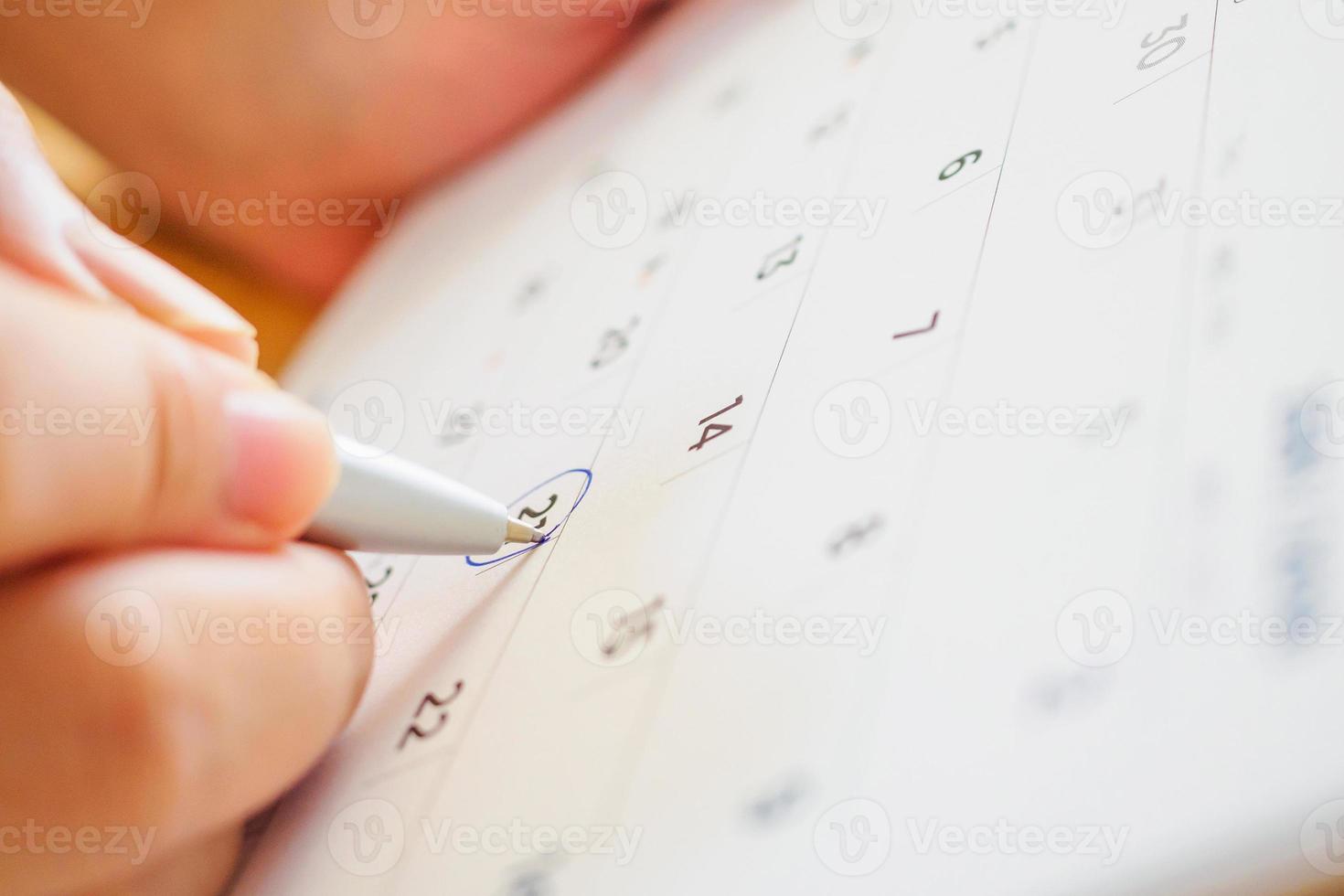 página do calendário com a mão feminina segurando a caneta foto