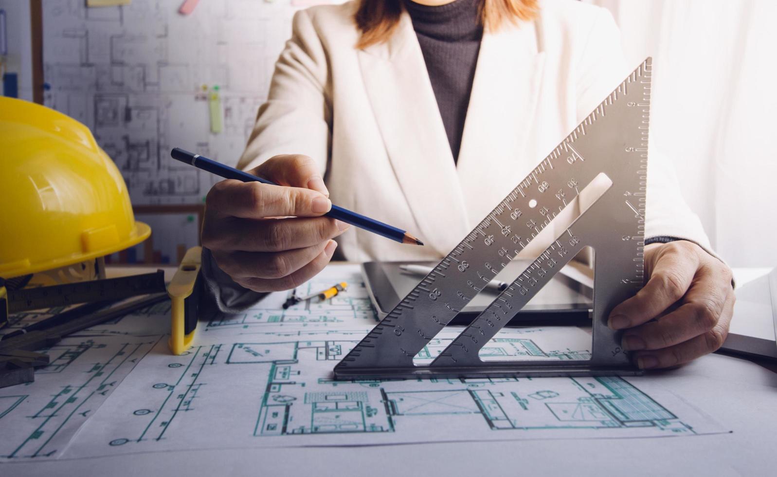 dois colegas discutindo dados de trabalho e tablet, laptop com projeto arquitetônico no canteiro de obras na mesa no escritório foto