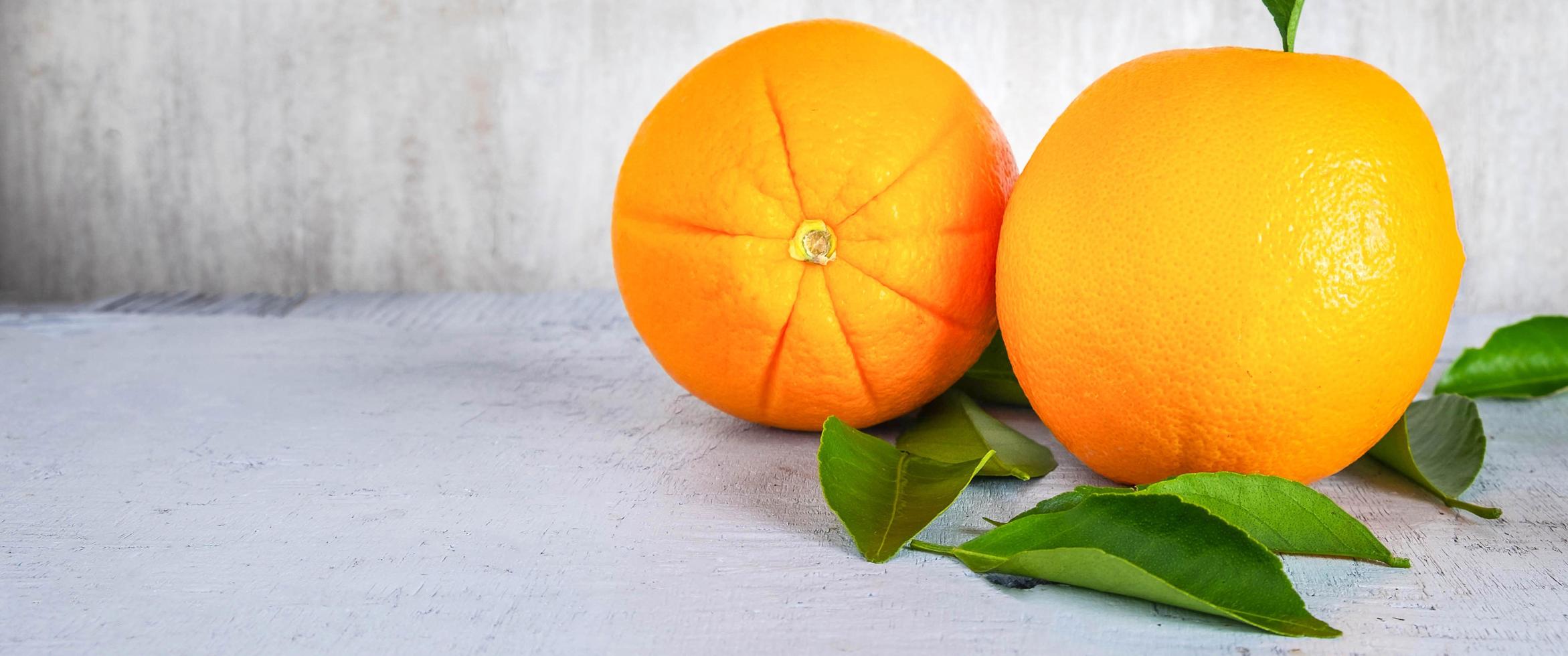 frutas frescas de laranja e folhas verdes sobre fundo branco de madeira. foto