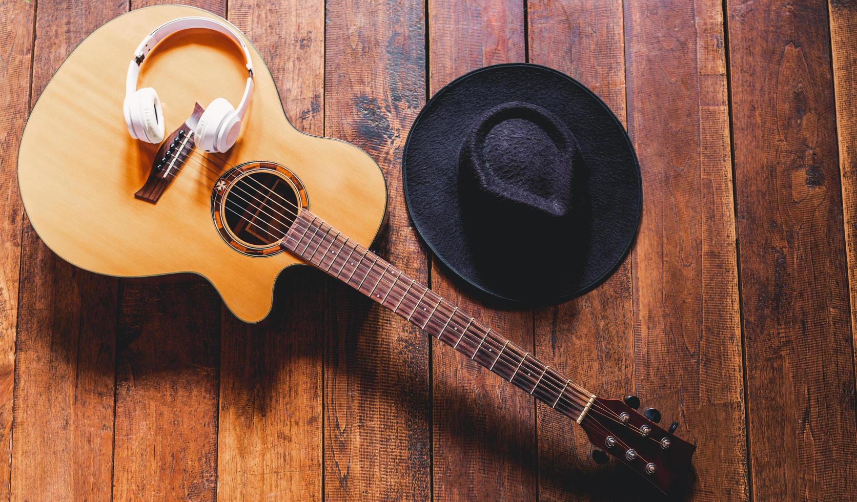 guitarras acústicas de vista superior com fones de ouvido e chapéus hipster em fundo de madeira velho. foto