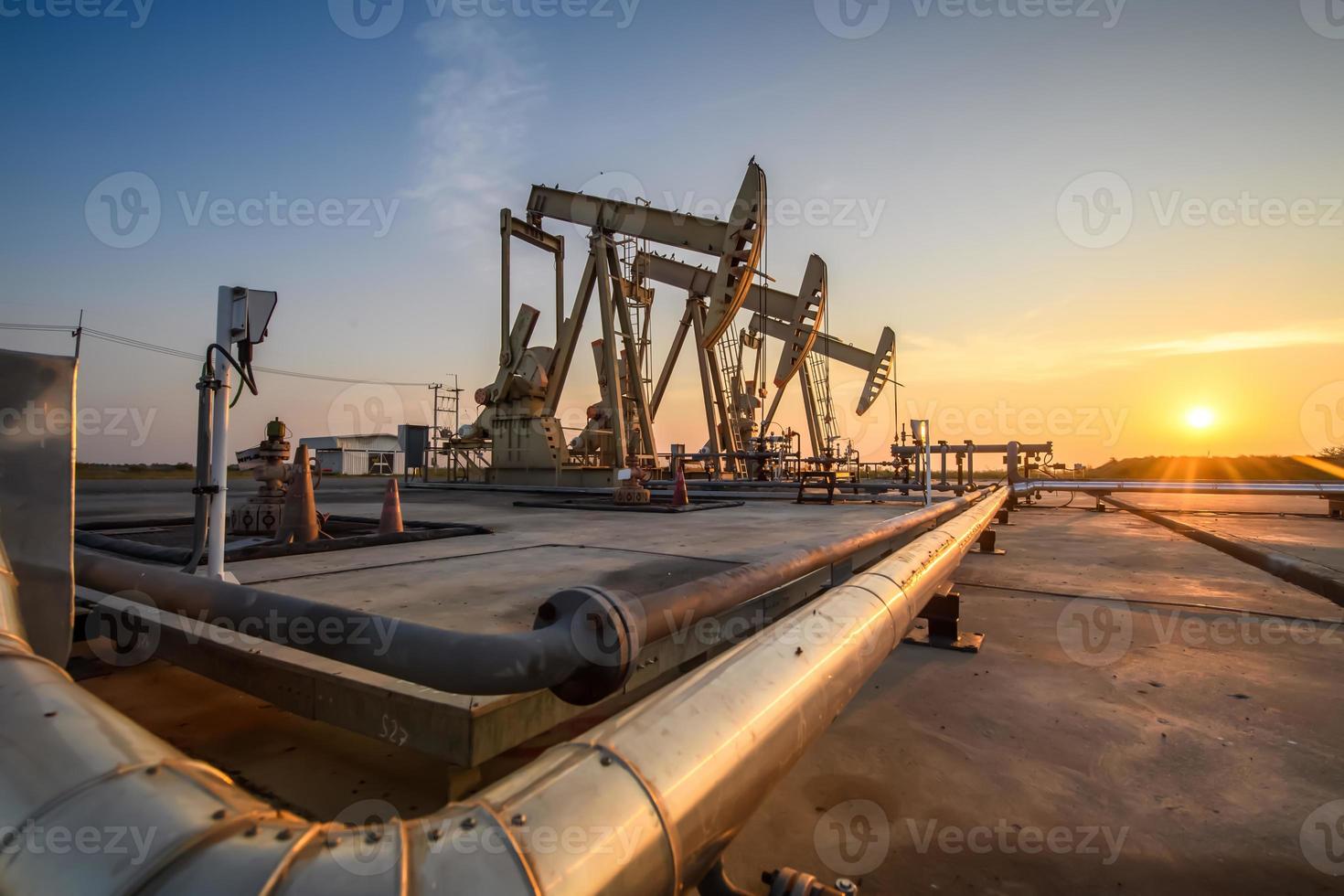 plataforma de petróleo ou campo de petróleo à noite, o posto de gasolina está funcionando. posto de gasolina e belo pôr do sol da unidade de bombeamento à noite. foto