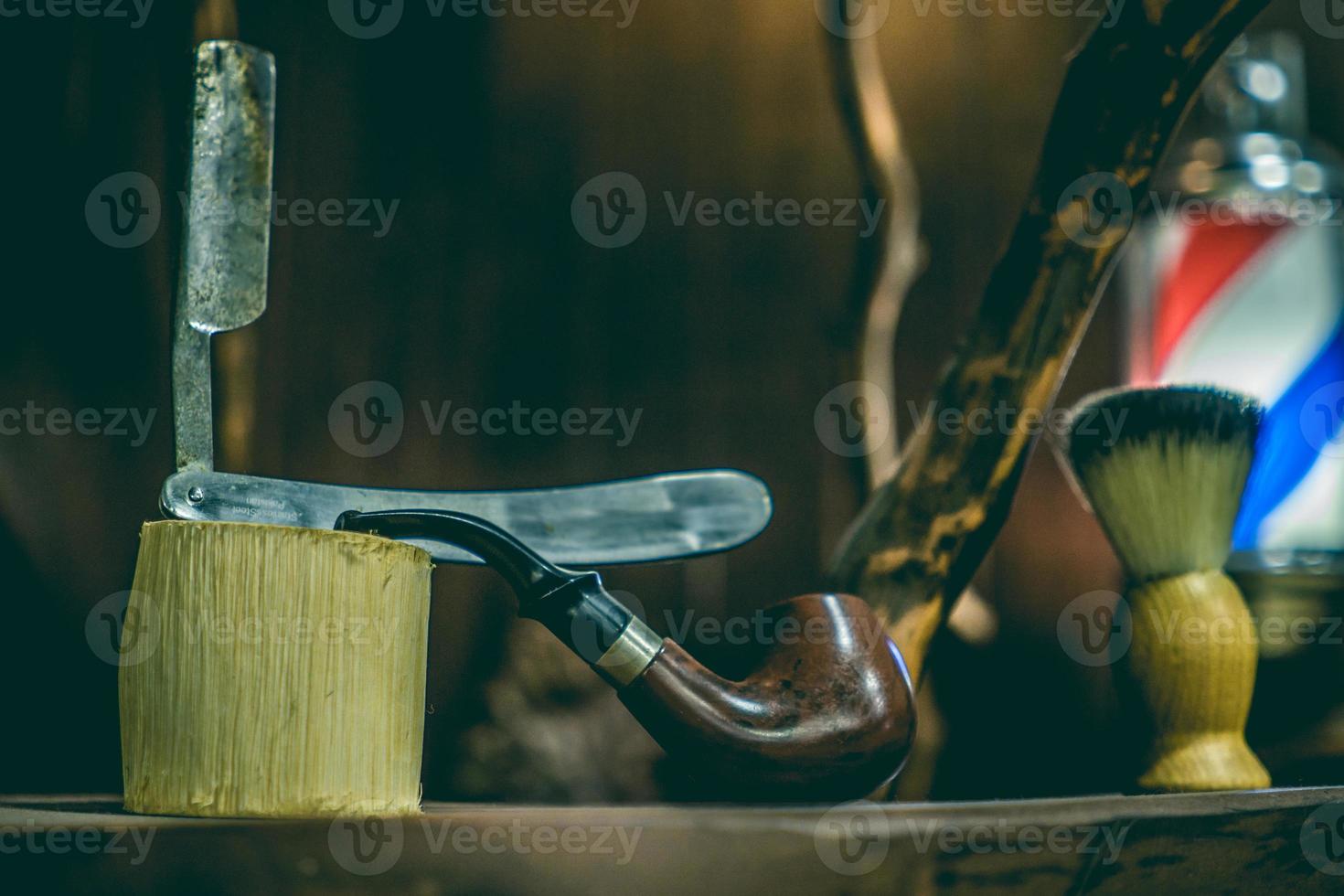 navalha, pincel e cachimbo antigo em uma prateleira de barbearia. foto