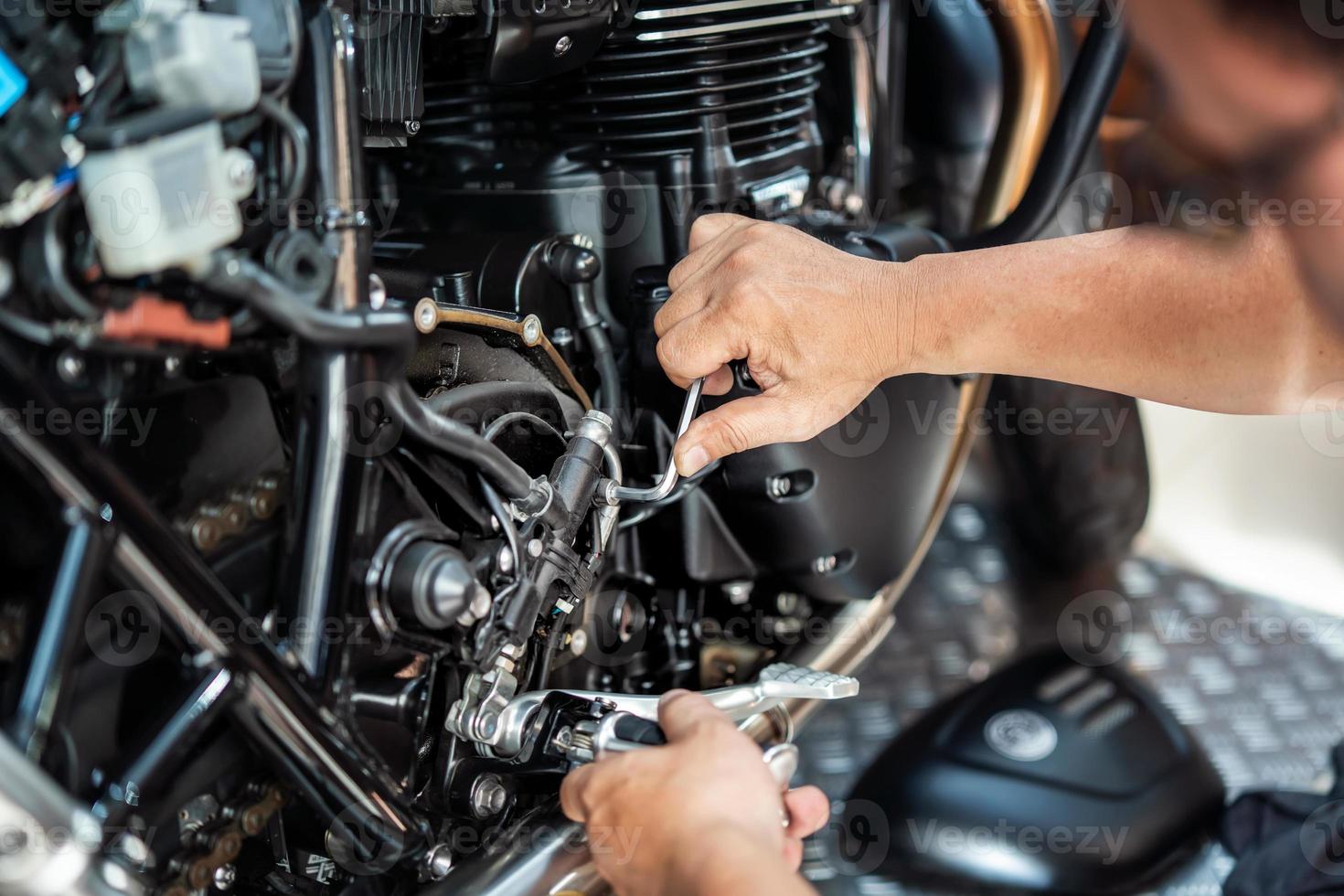 mecânico usando uma chave hexagonal ou chave allen para remover a bomba de freio hidráulica traseira da motocicleta, trabalhando na garagem .manutenção e reparo conceito de motocicleta .foco seletivo foto