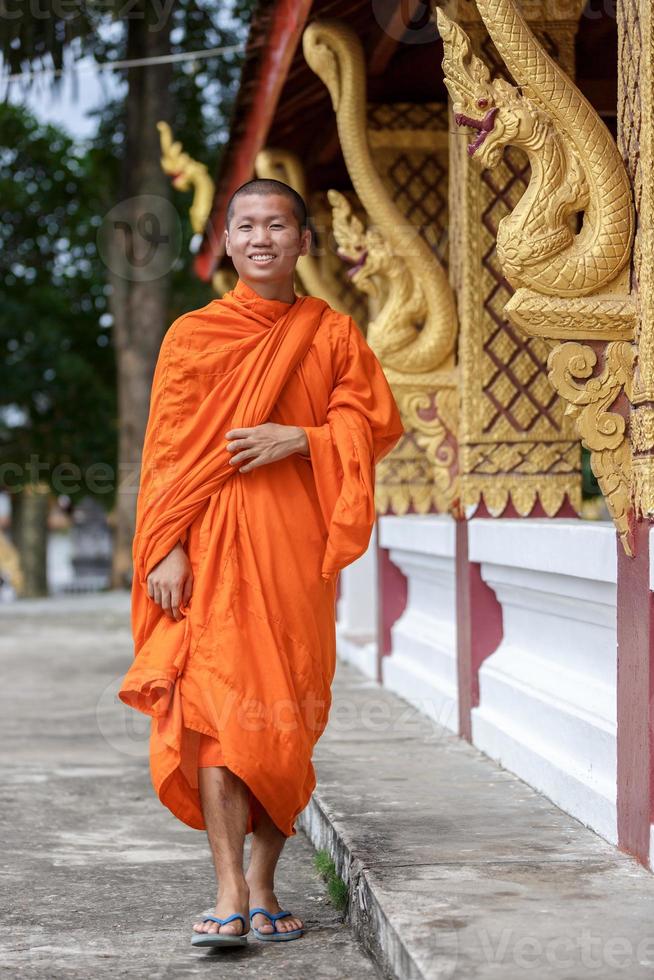 jovem monge budista andando ao lado do templo foto