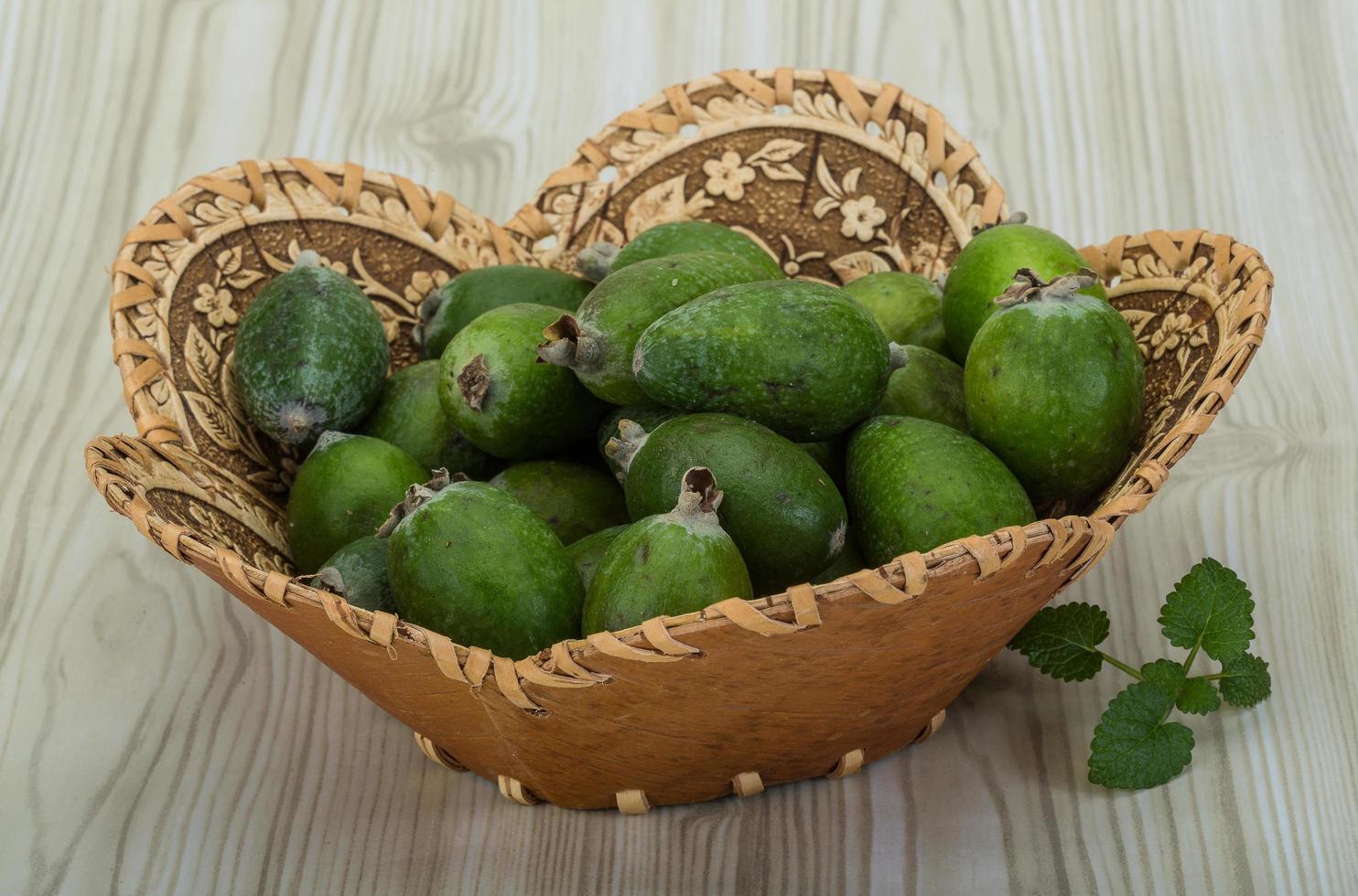 feijoa em uma cesta em fundo de madeira foto