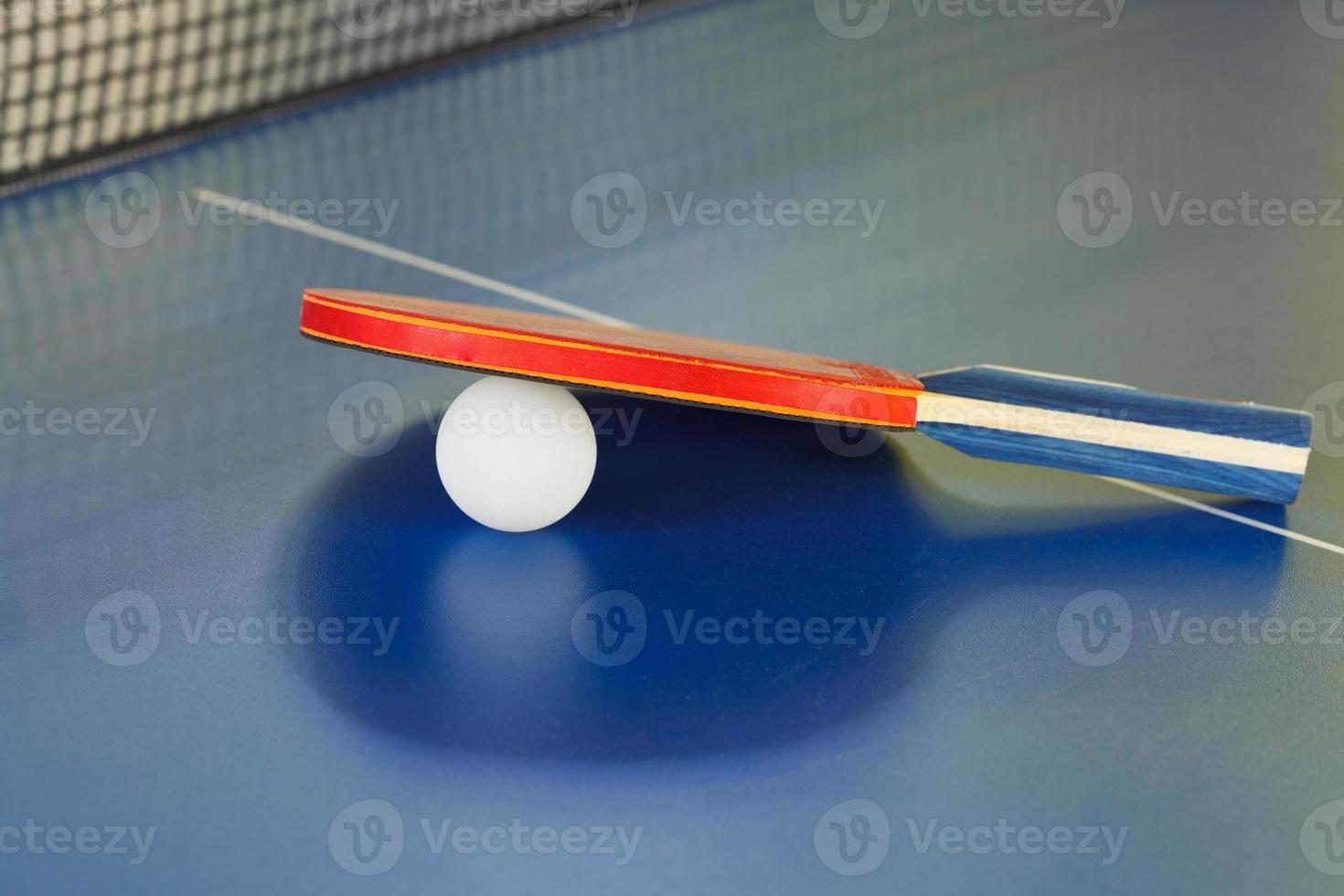 raquete, bola de tênis na mesa de ping pong azul foto
