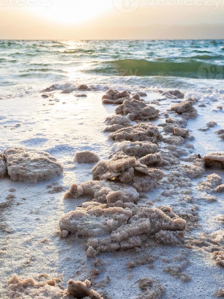 sal cristalino na costa do mar morto no pôr do sol foto