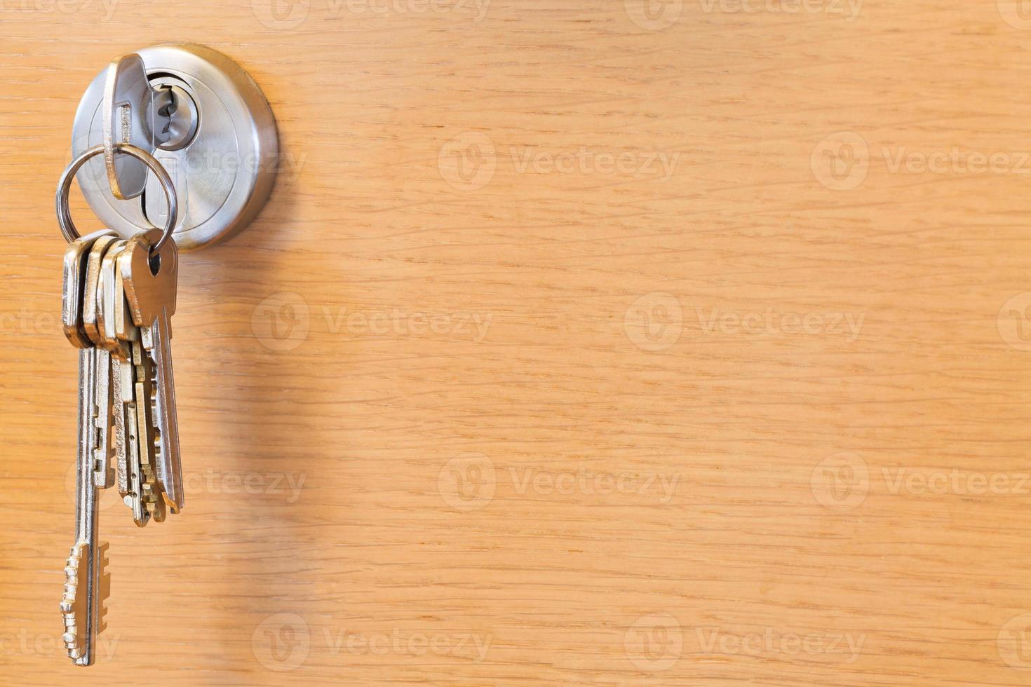molho de chaves na fechadura da porta de madeira foto