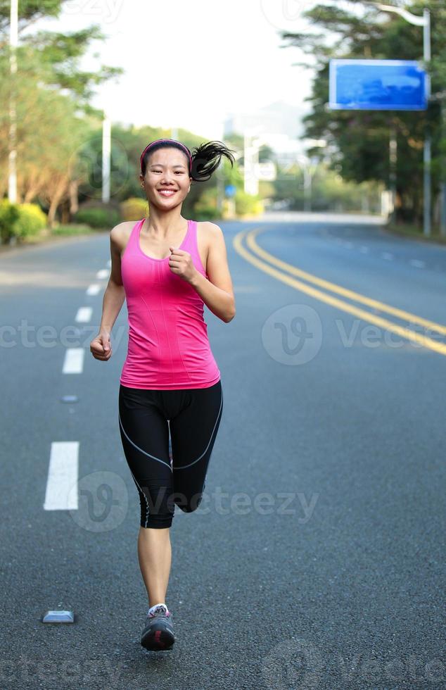 mulher asiática de esportes correndo na estrada da cidade foto