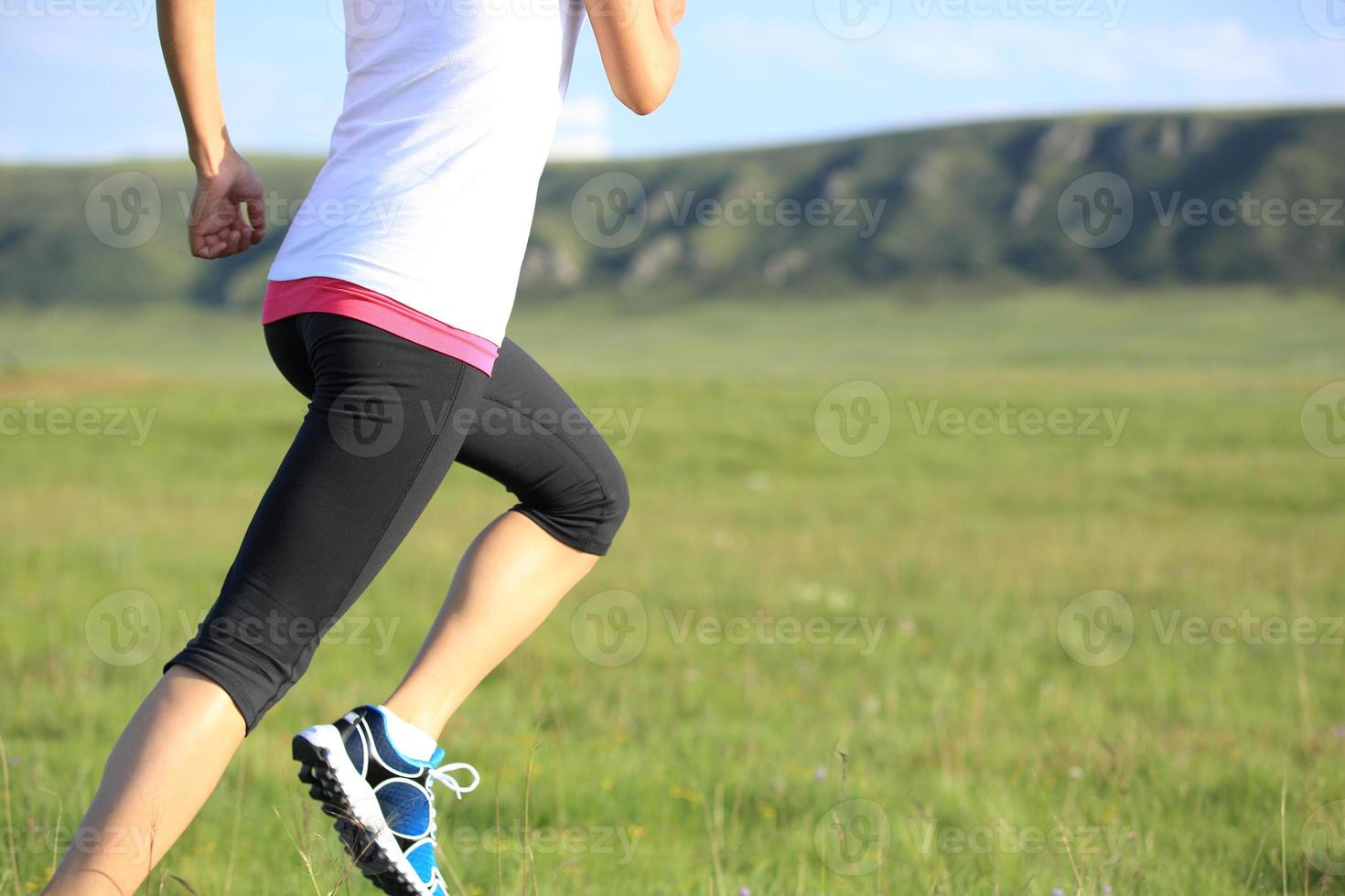 atleta corredor correndo no campo de grama ensolarada foto