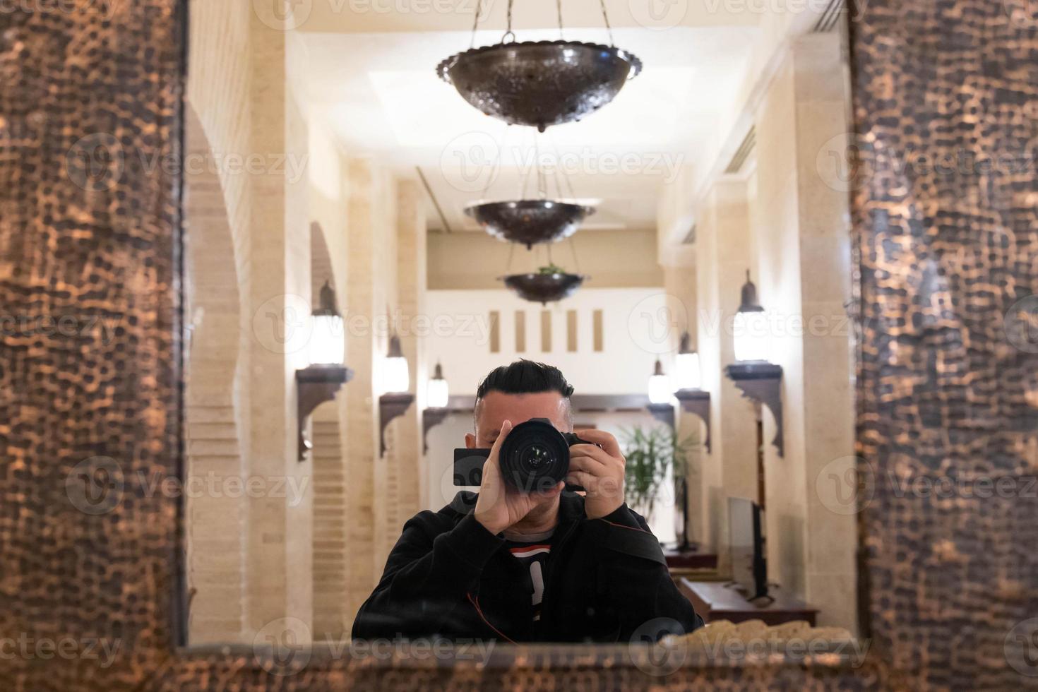 foco seletivo suave da lente com fotógrafo masculino turva tirando foto de si mesmo no espelho, close-up vista de um homem segurando uma câmera fazendo retrato.