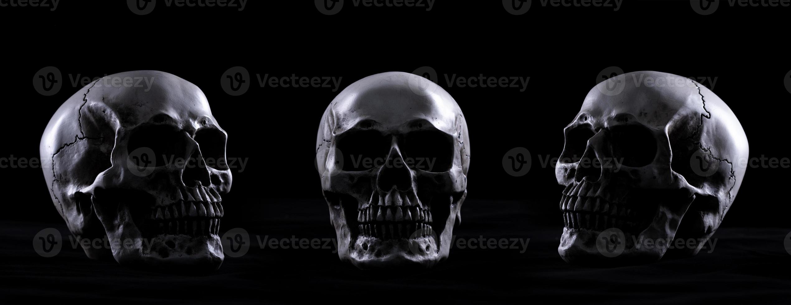 crânio humano de halloween em uma velha mesa de madeira sobre fundo preto. forma de osso do crânio para a cabeça da morte no festival de halloween que mostra o mal de horror. vista frontal esquerda direita, copie o espaço foto