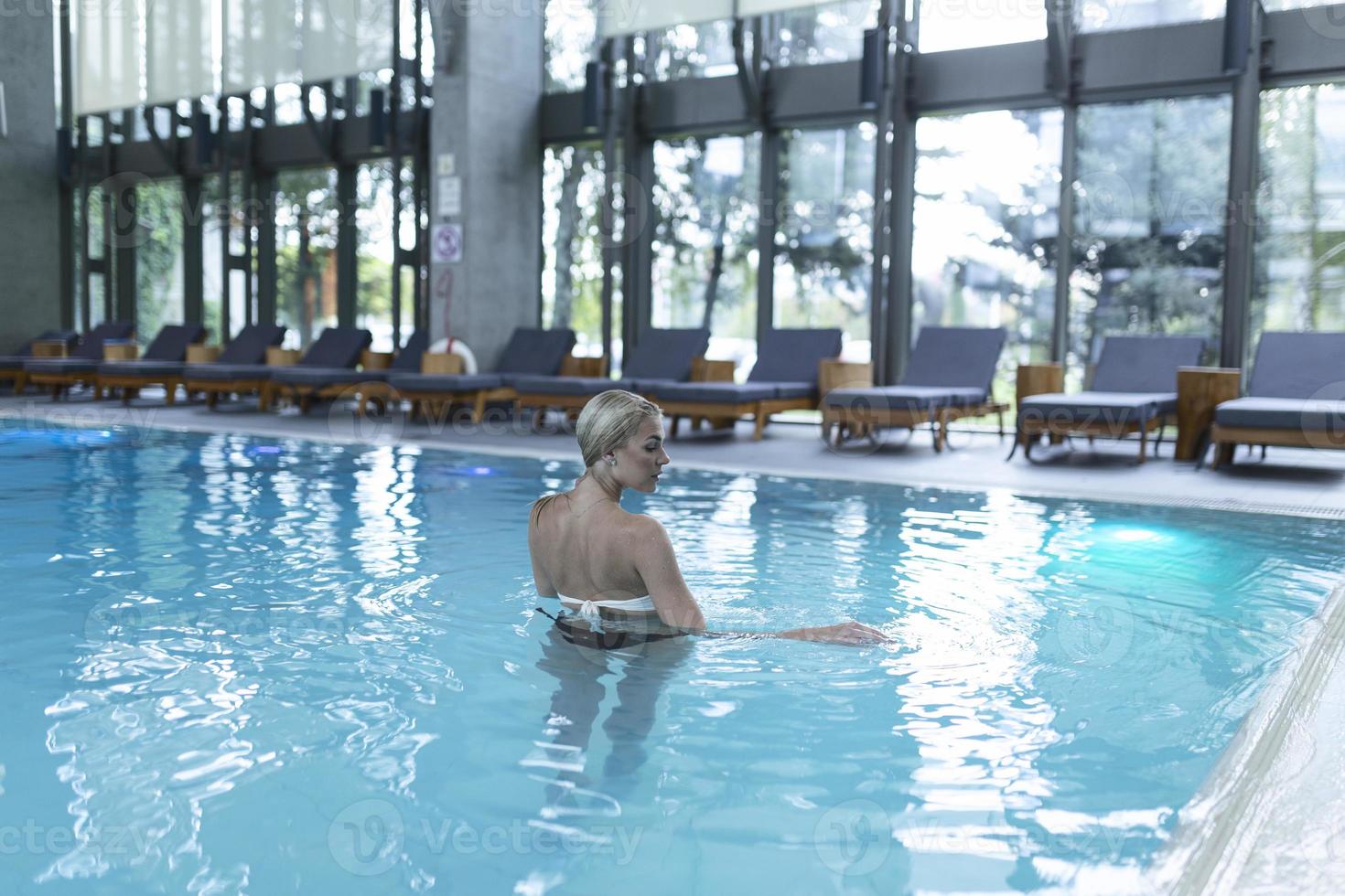 vista lateral de uma mulher caucasiana descansando à beira da piscina. ela está curtindo um fim de semana tranquilo no spa. foto