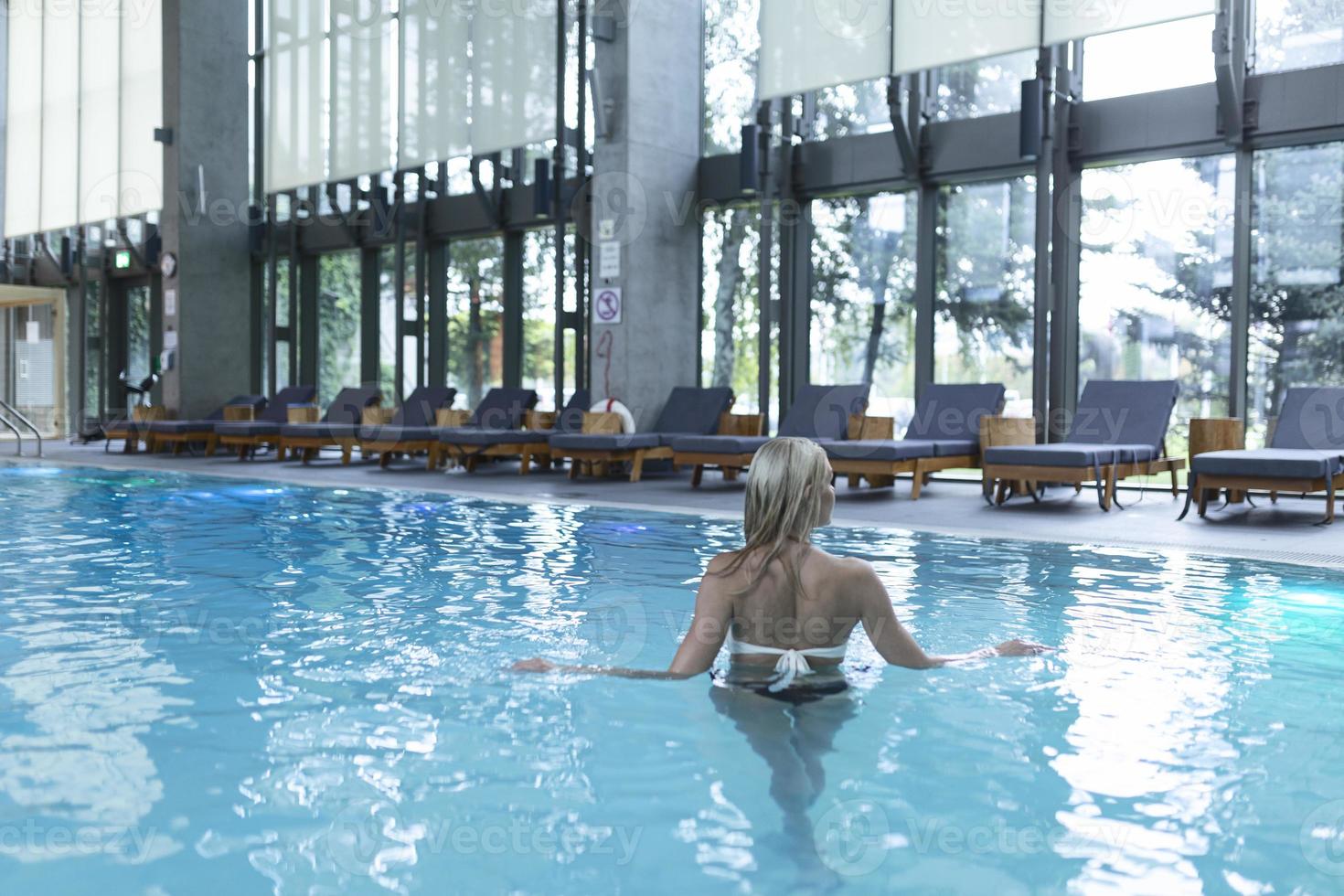 vista lateral de uma mulher caucasiana descansando à beira da piscina. ela está curtindo um fim de semana tranquilo no spa. foto