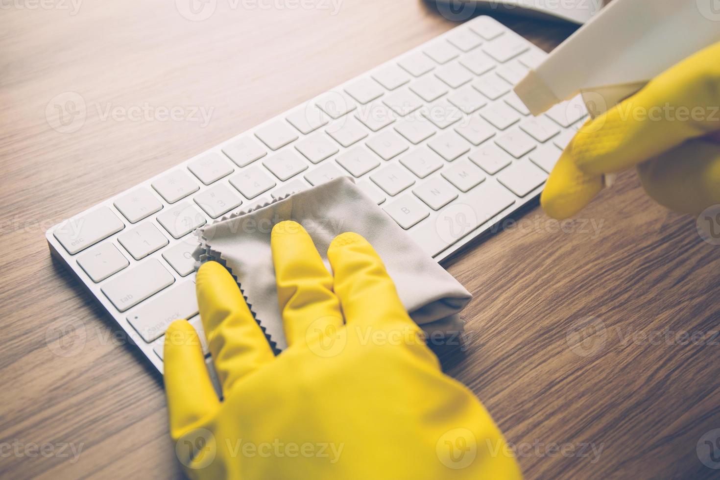 mão do homem limpando o teclado do computador com antibacteriano para proteger a doença epidêmica covid-19, tecido com álcool anti-séptico limpo e laptop de lavagem para o conceito de mesa, negócios e saúde. foto