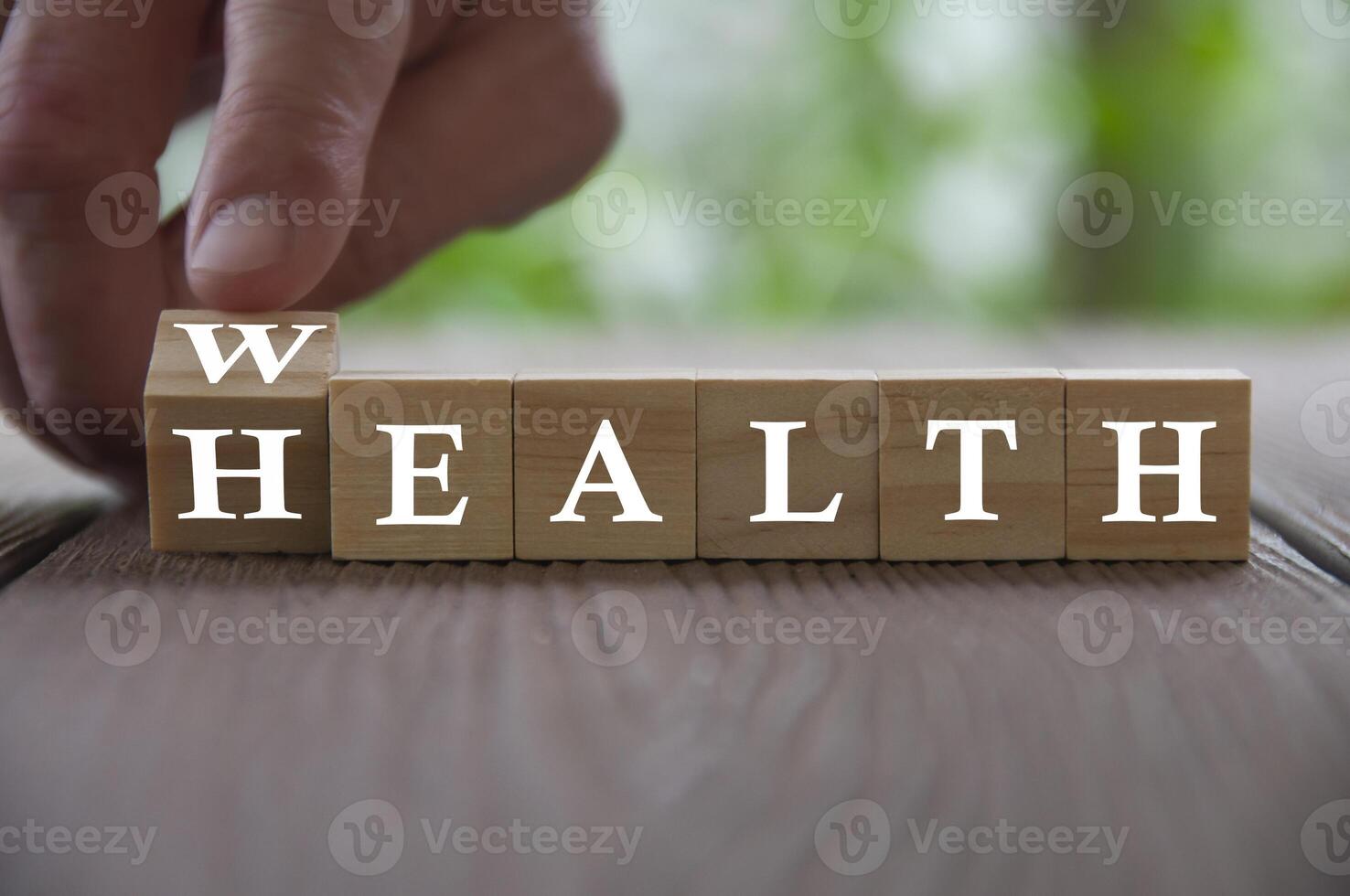 mão flip cubo de madeira com palavra riqueza para a saúde com fundo desfocado da natureza. conceito de riqueza e saúde foto