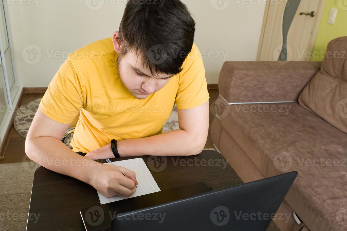 o adolescente em casa estudando no laptop foto