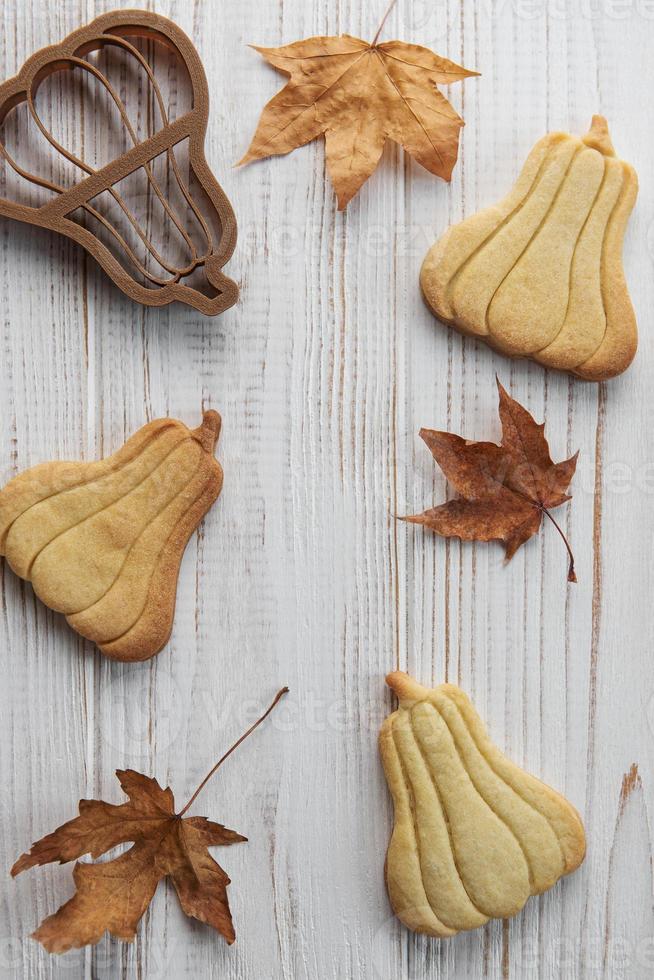 biscoitos em forma de abóbora e folhas em fundo de madeira rústica foto